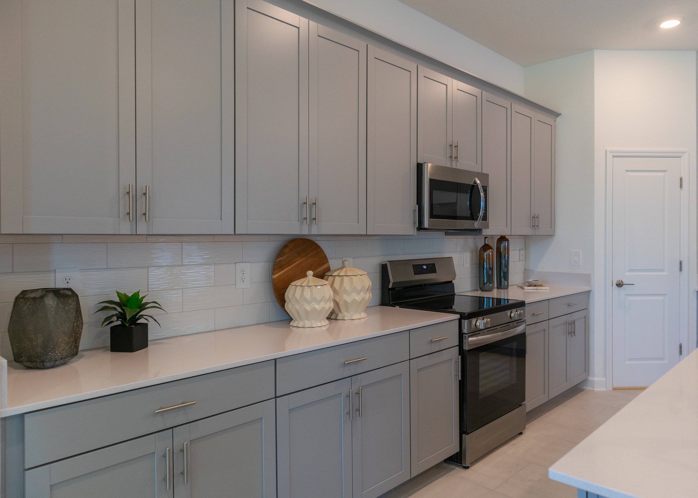 Wall of cabinets and countertop in new kitchen with stove and microwave