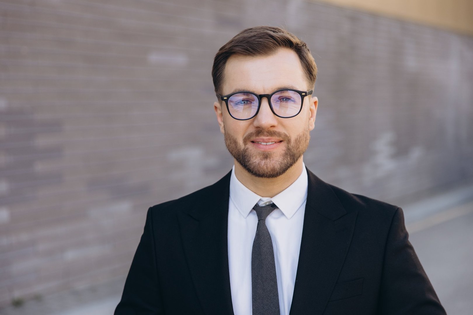 Portrait of Confident Businessman Smiling Wearing Suit and Glasses in Urban Setting