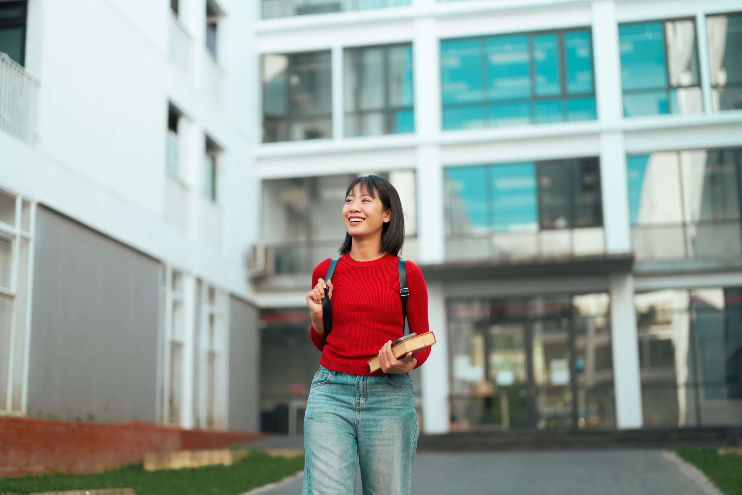 Happy Asian female student walking outdoors on university campus