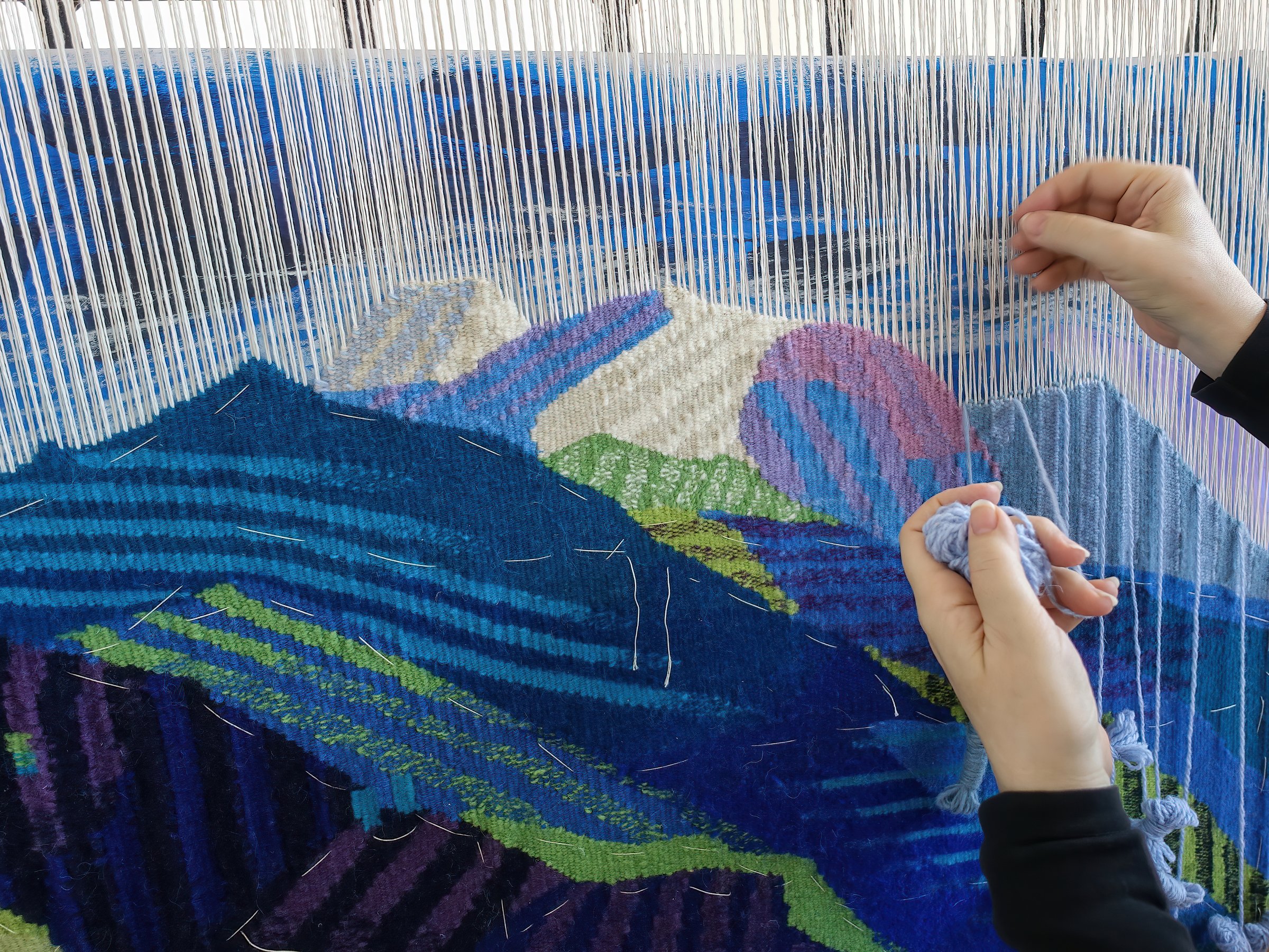 Woman's hands making tapestry with colorful wool, manufacturing