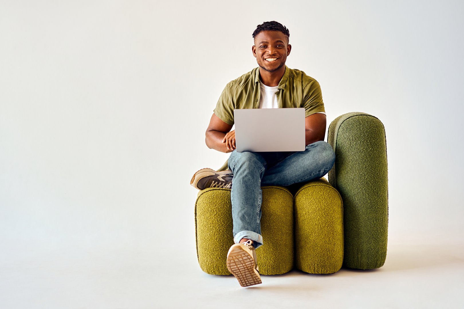 Male freelancer in casual attire looking at camera with toothy smile over white background.