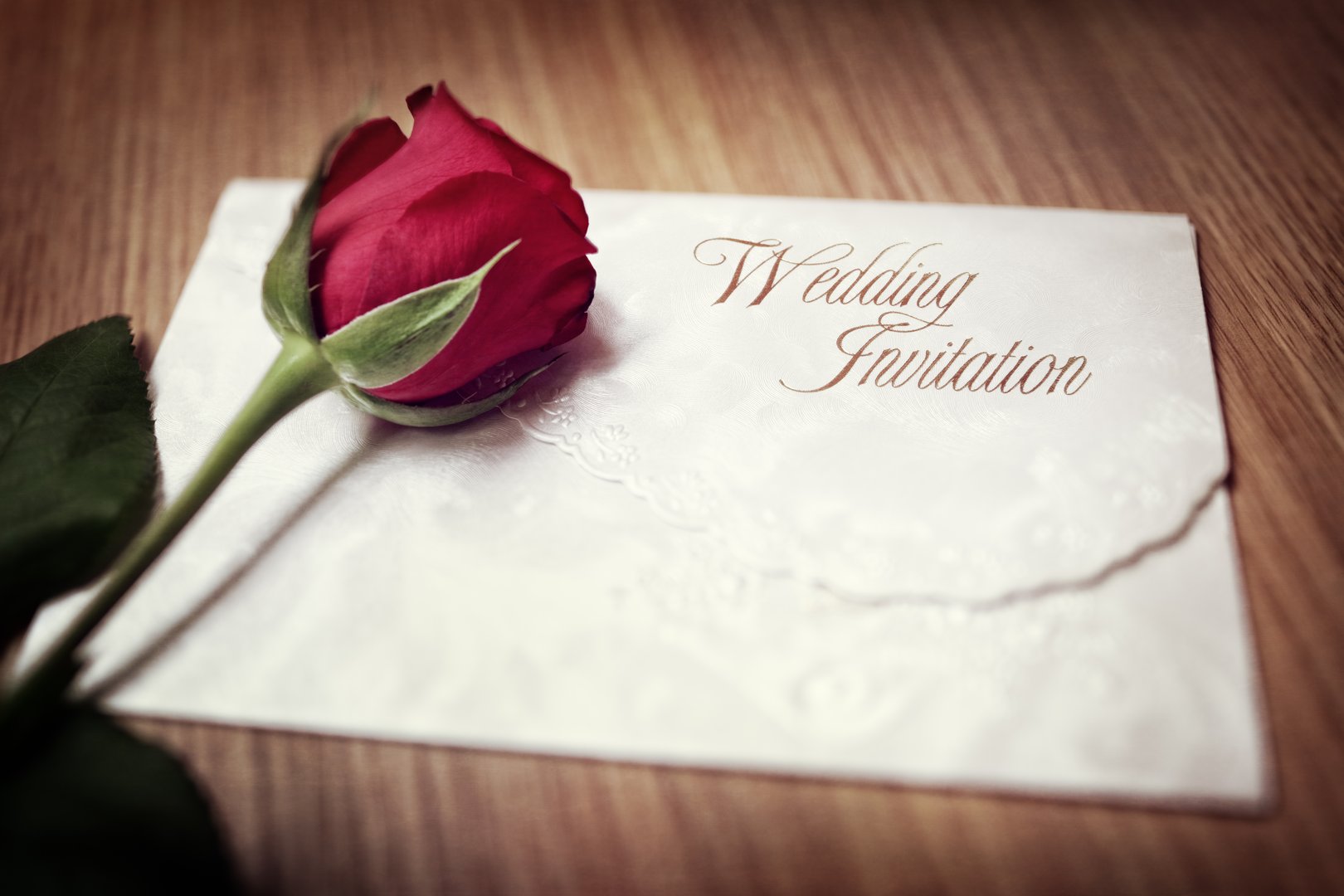 Wedding invitation and red rose on a wooden table