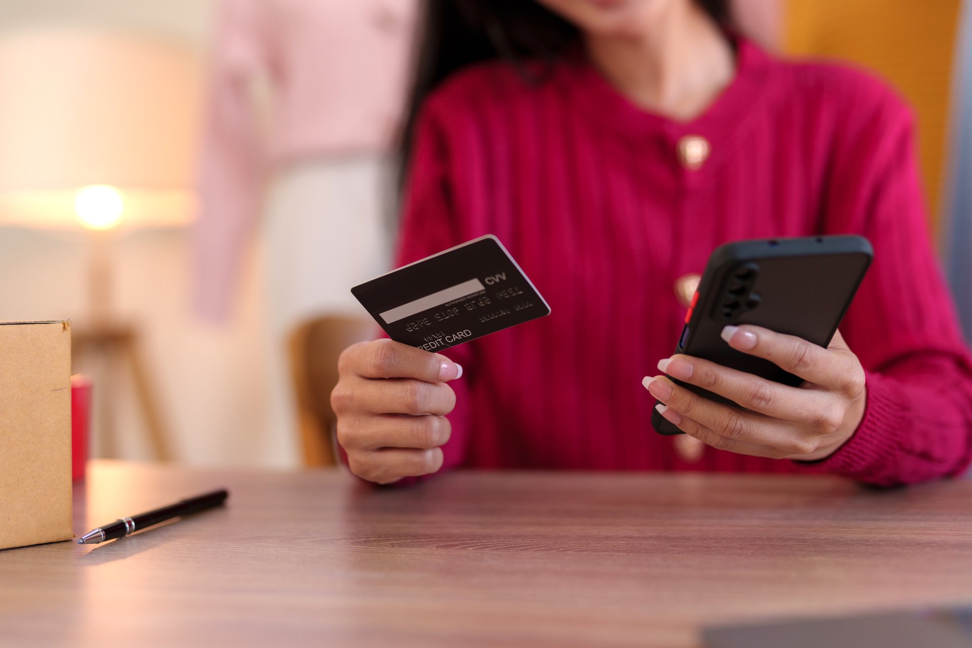 Young business woman is using smartphone for online shopping and using credit card for payment through banking application for online shopping.