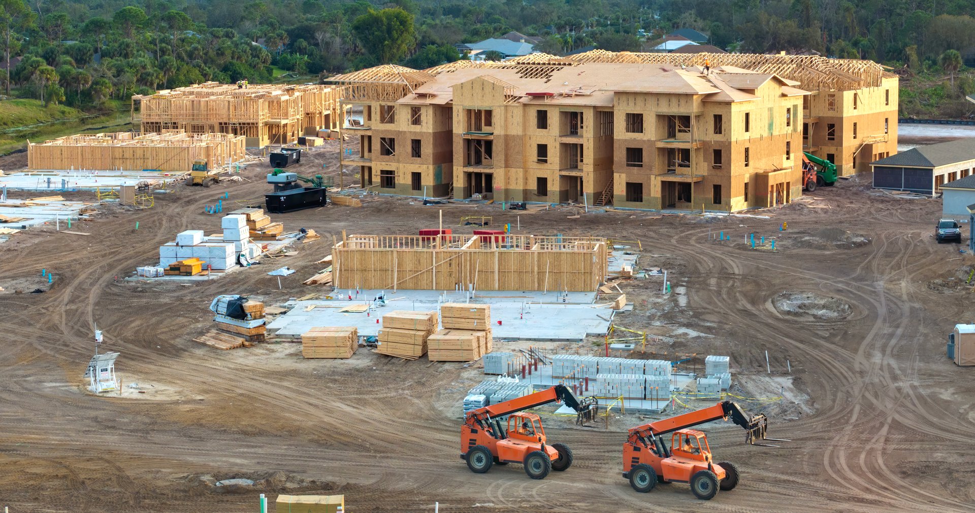 Development of residential housing in American suburbs. Unfinished frames of apartment condos with wooden roof beams under construction. Real estate market in the USA.