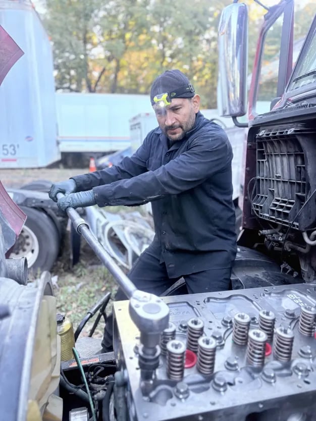 Semi Truck Under Maintenance. Caucasian Truck Mechanic Working to Fix the Tractor