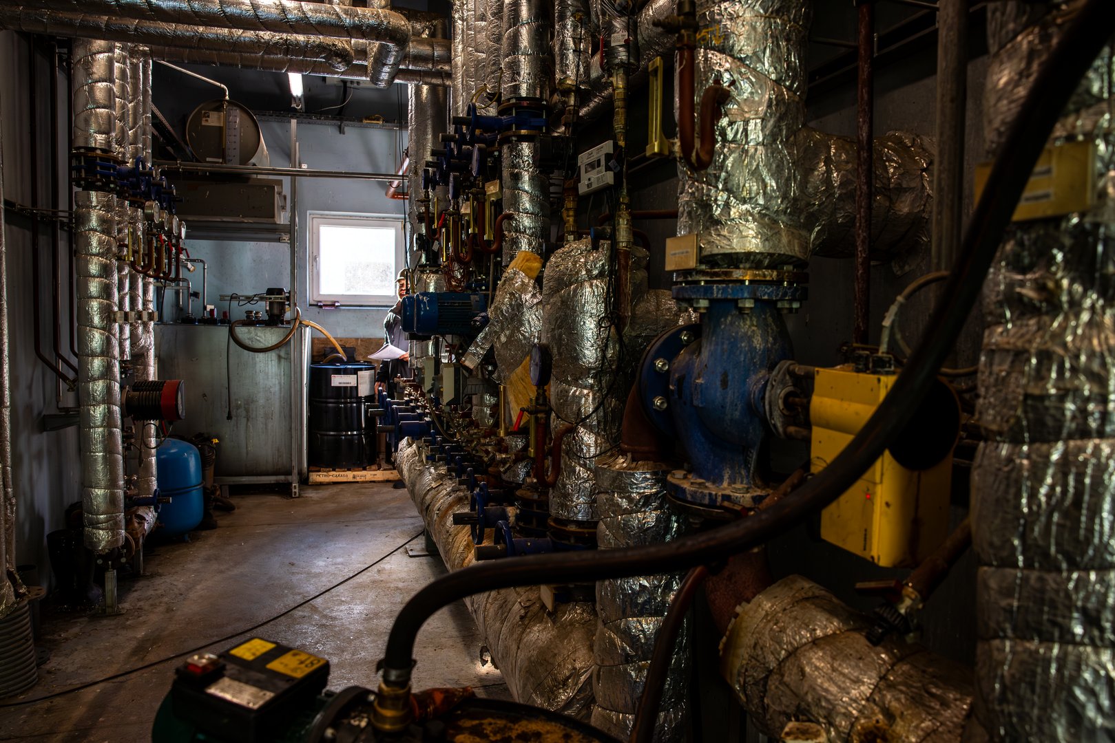 Mechanical room with insulated pipes, gauges, valves, and blue pump