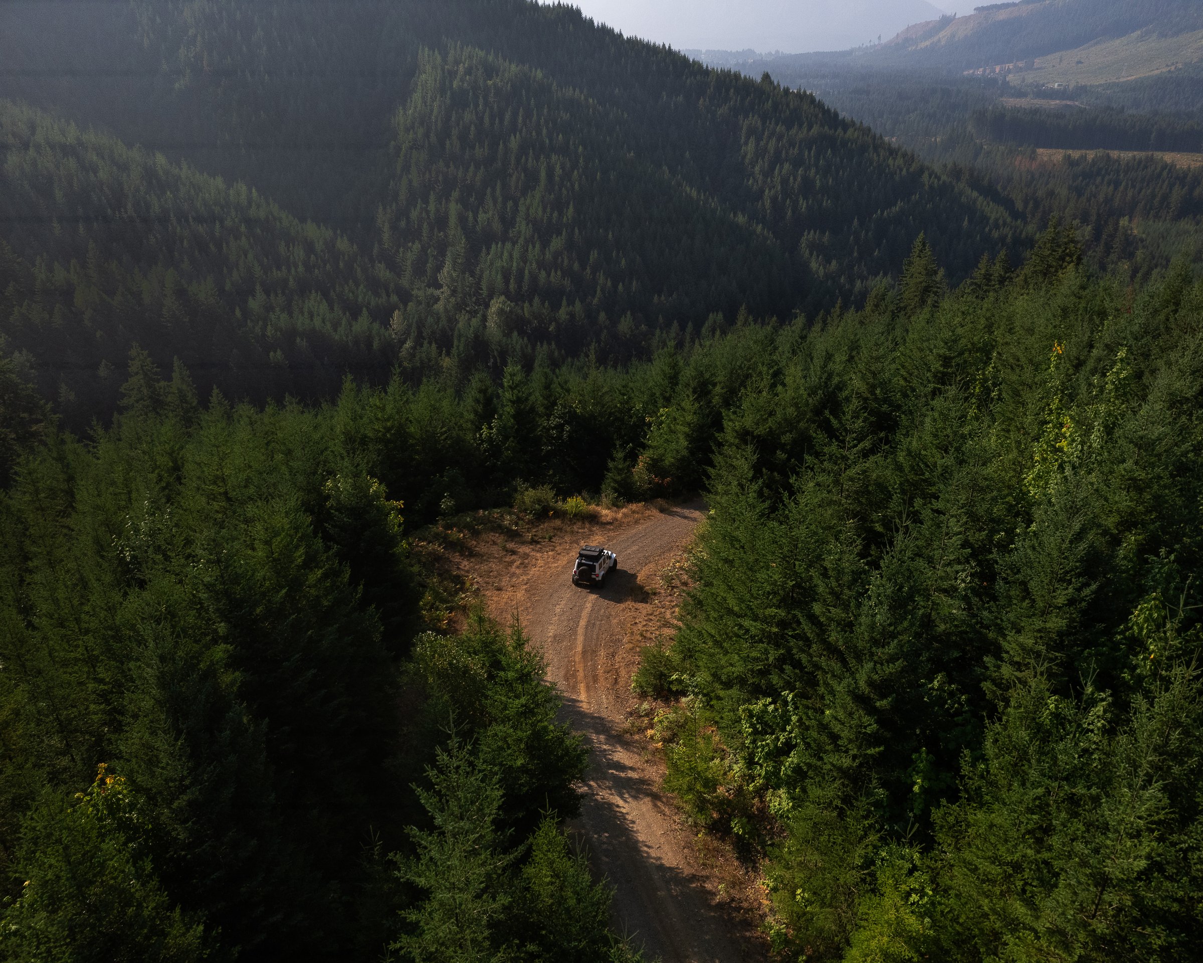 Drone photography of a over landing vehicle driving through forested roads