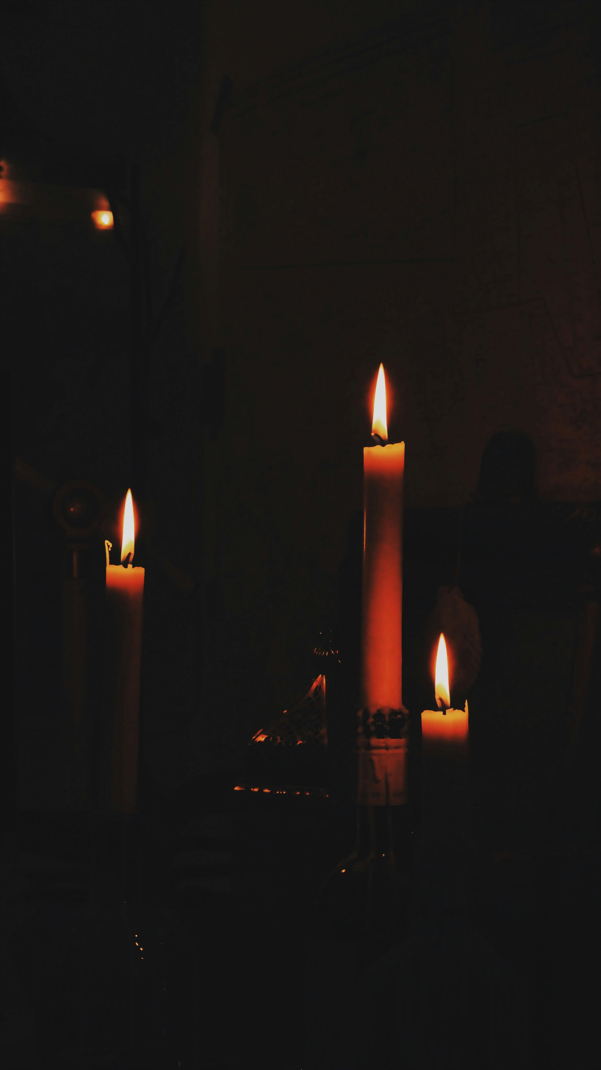 Three lit candles in a dark room casting a warm glow.