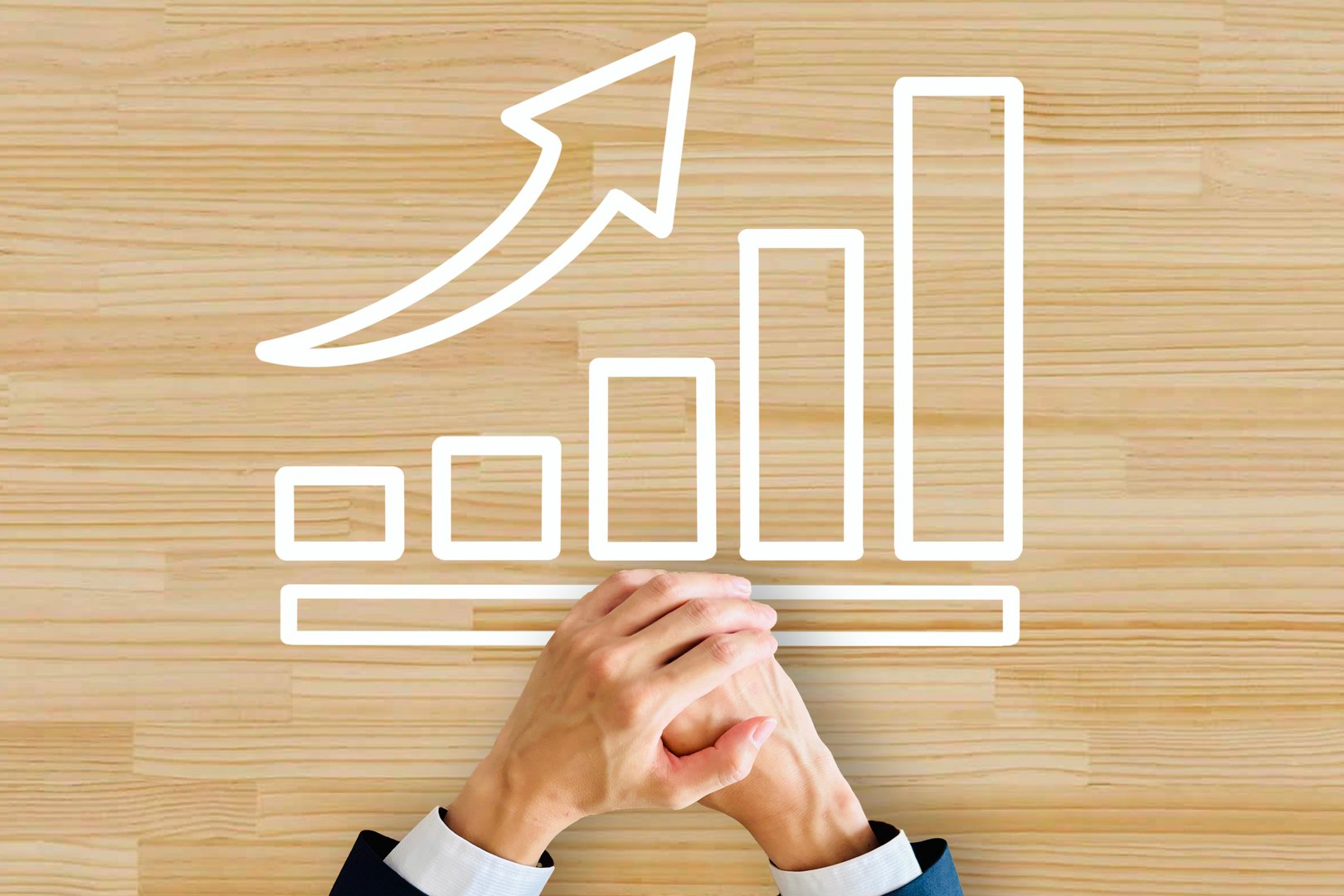 Hands folded on a wooden table overlaid with an upward bar graph, representing growth, improvement, and success.