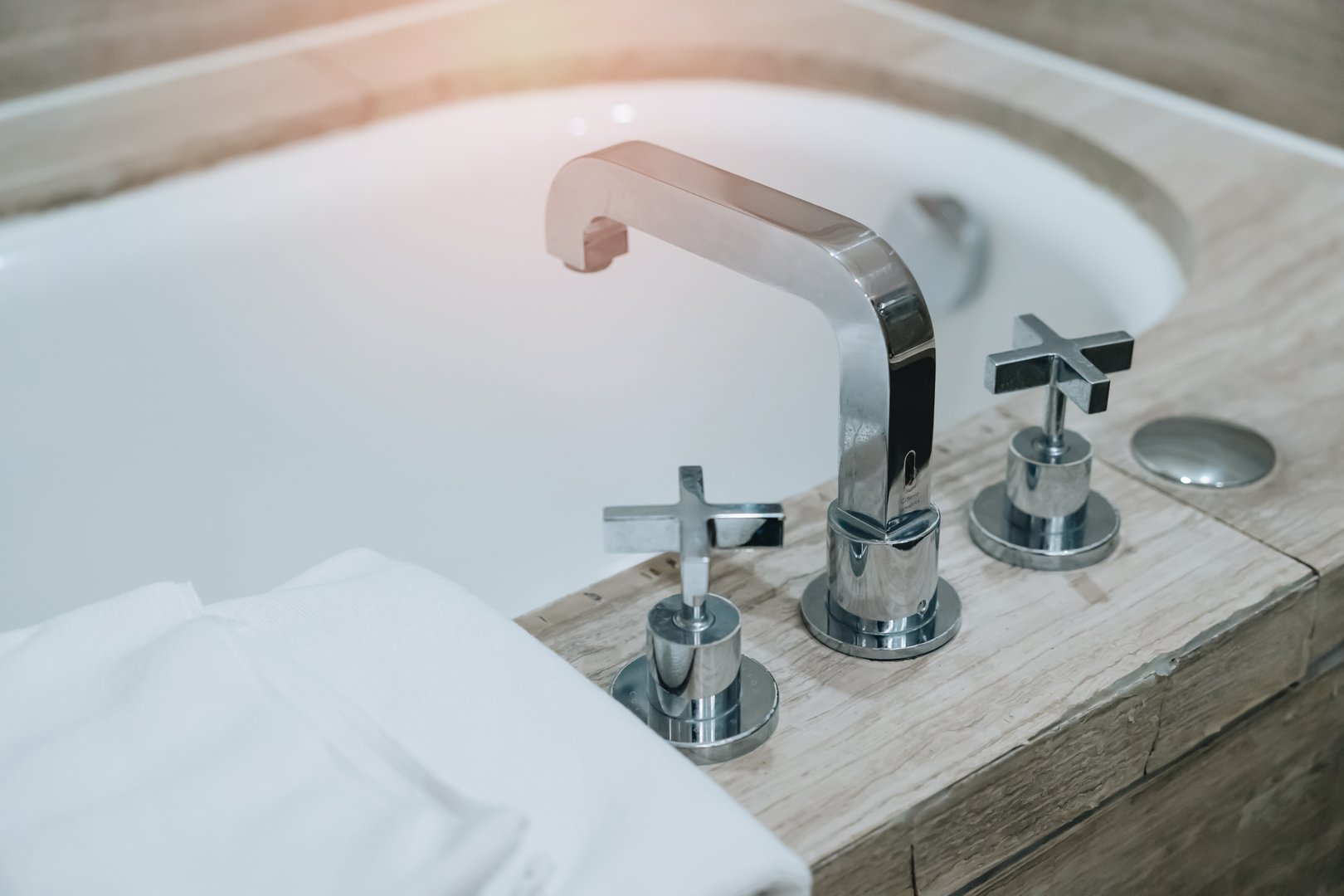 Bathtub in hotel. Modern Bathroom Sink Faucet with Stylish Taps and Soft Towels next to an Elegant Bathtub in a Relaxing Spa Environment.