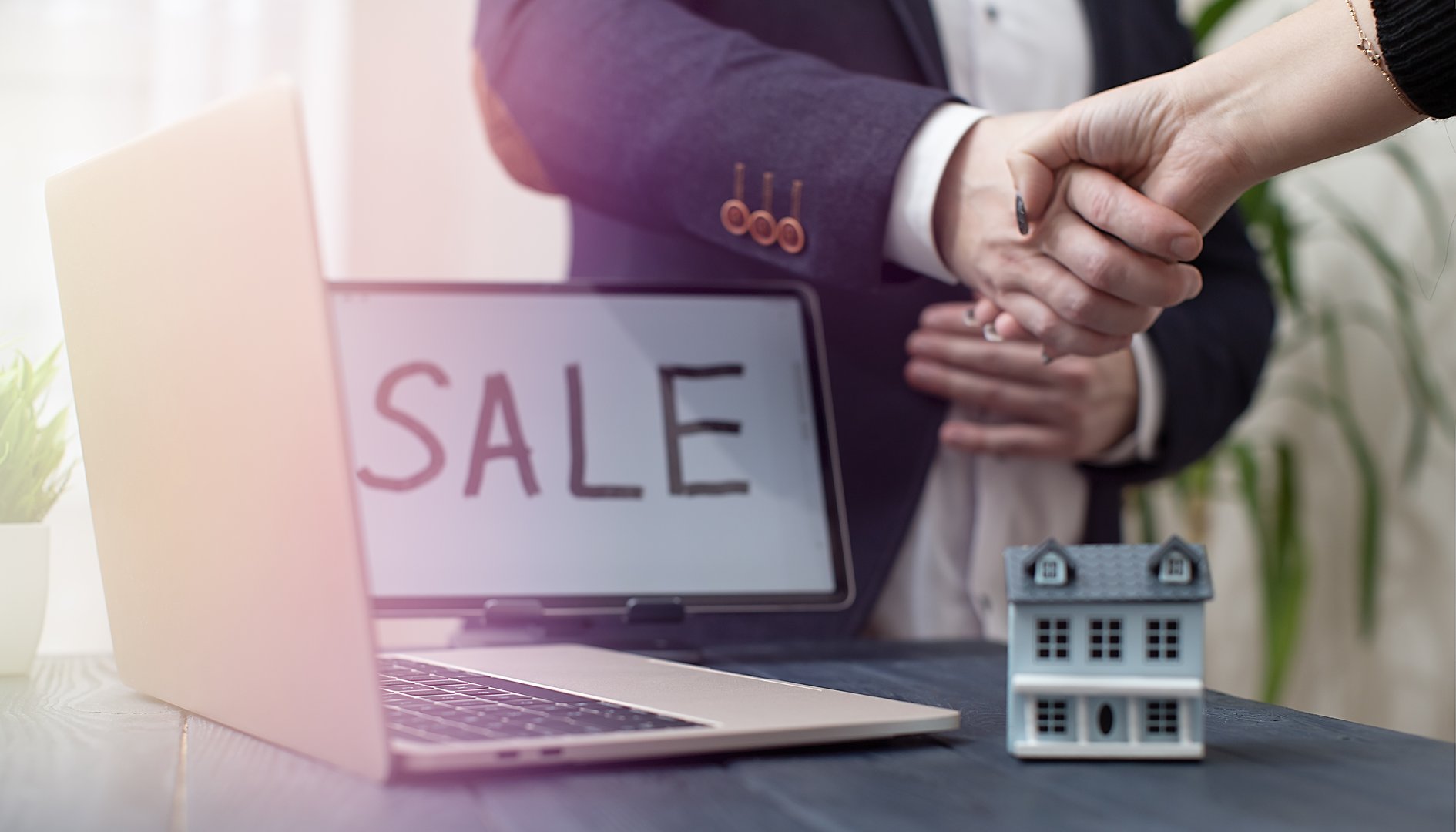 Handshake Agreement in Real Estate Sale with Laptop and Model House