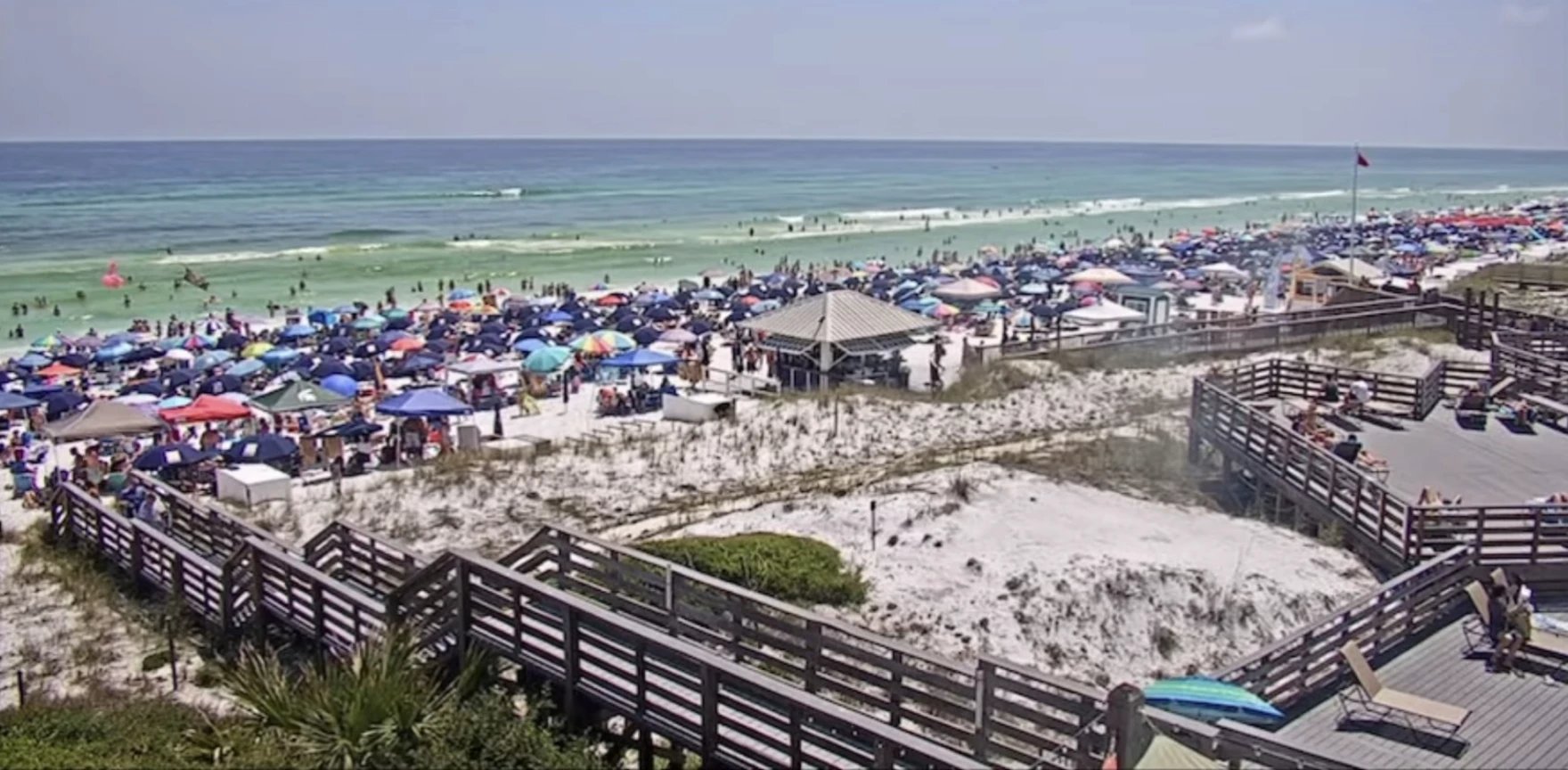Busy crowded Destin beach scene with umbrellas and people representing resort atmosphere