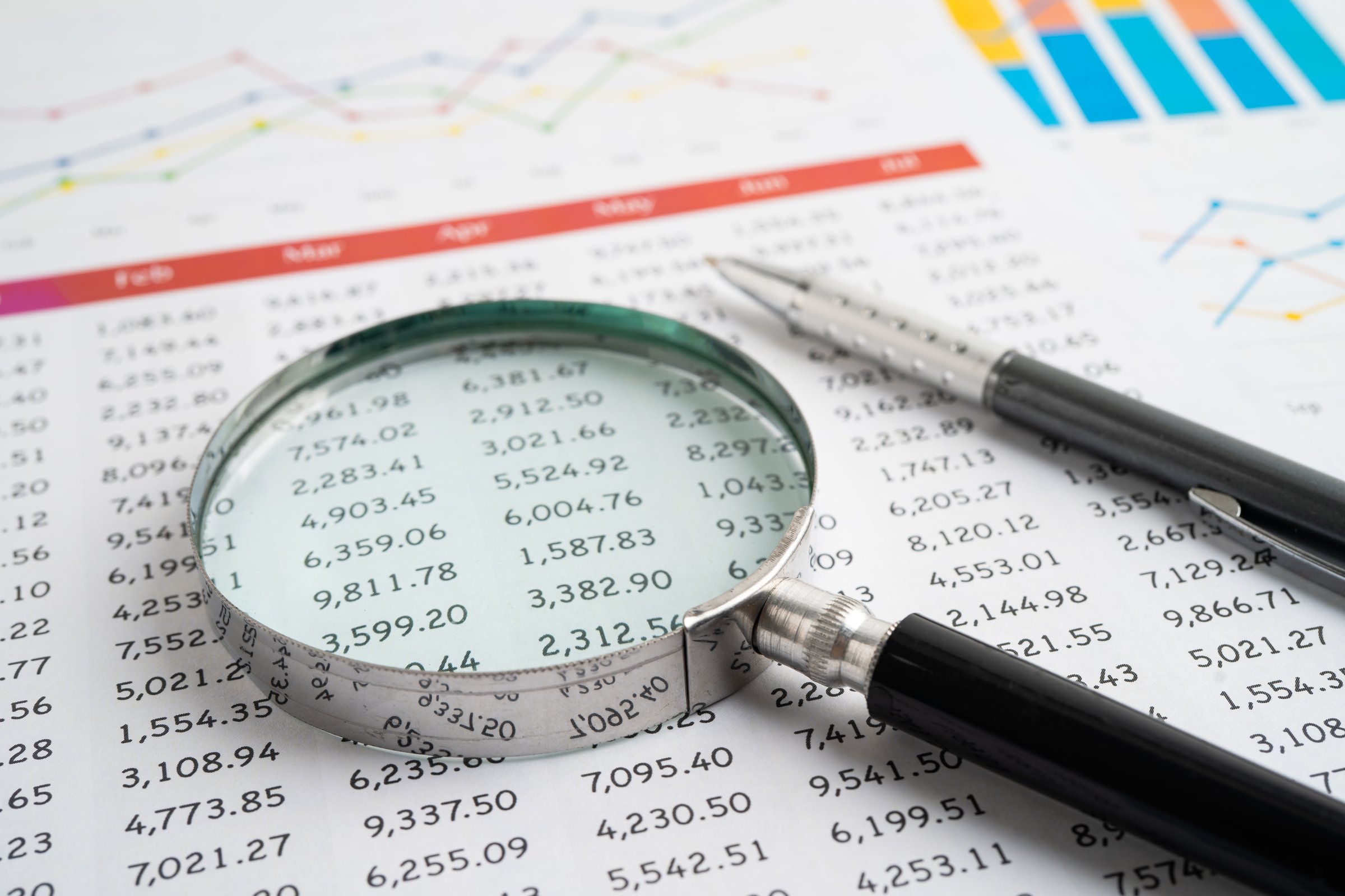 Magnifying glass on spreadsheet and graph paper. Financial data economy, Business.