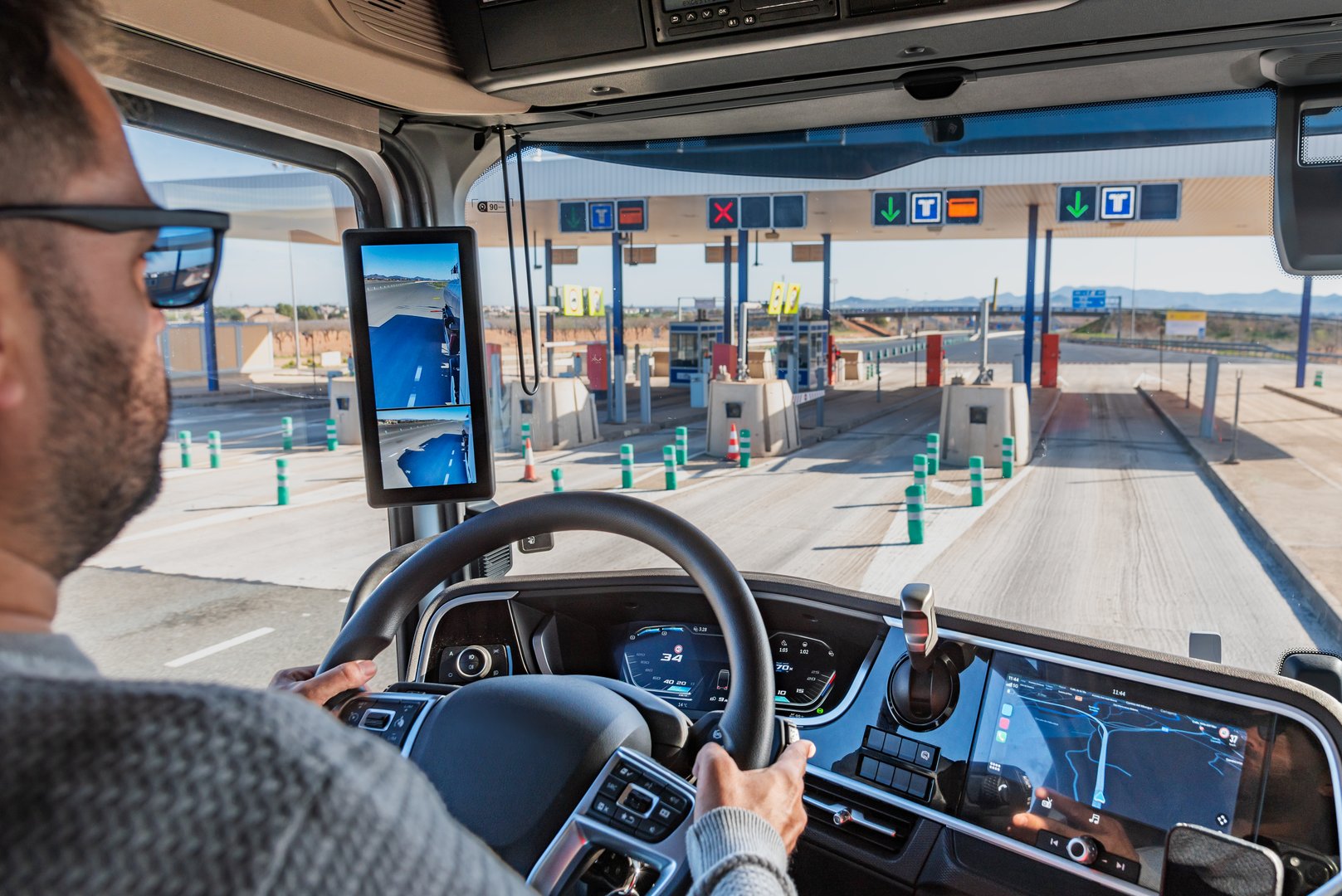 Almeria,1/19/2025; Truck driver operating a heavy vehicle and entering a toll gate marked with T, a fast lane for trucks.