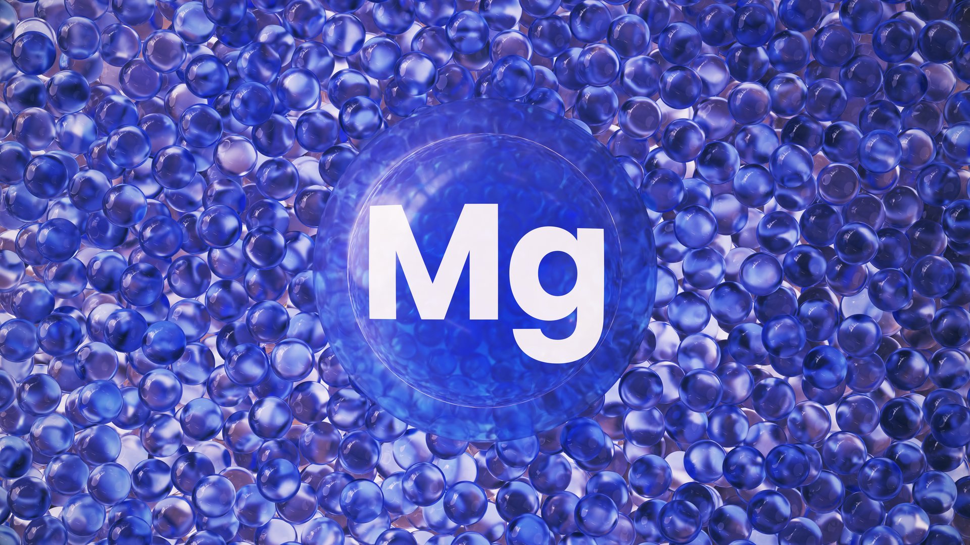 A modern 3D rendering featuring a large blue transparent capsule marked with the letter Mg, surrounded by small glossy gel-like spheres