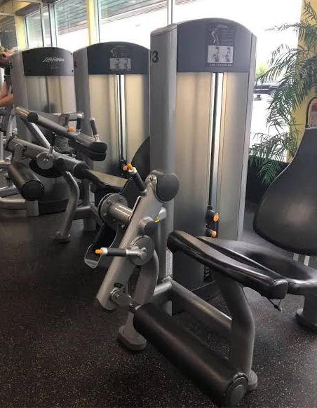 Gym equipment including seated leg curl and weight machines in a fitness center.