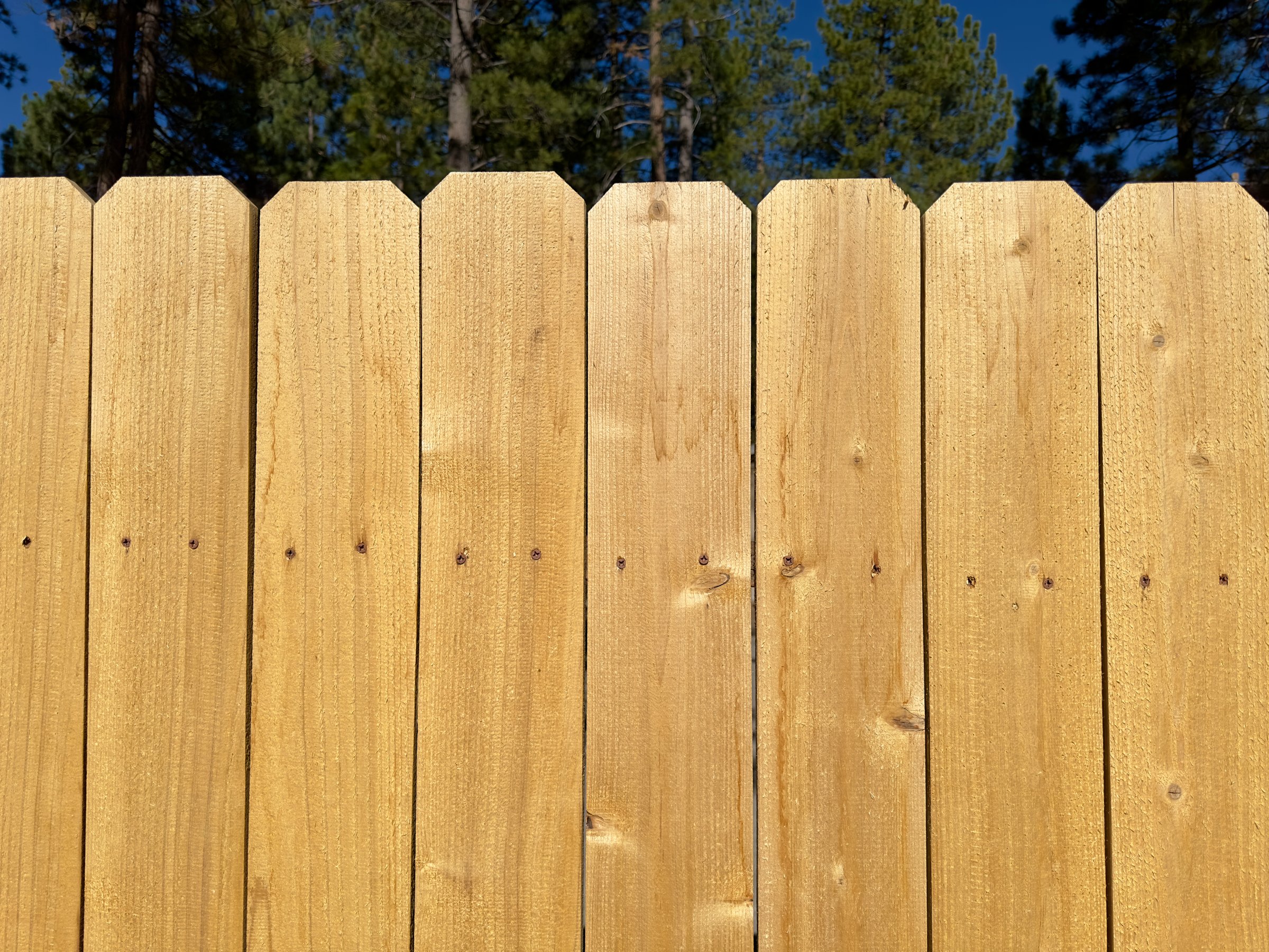 A rustic wooden fence encloses the backyard, adding charm and privacy to the outdoor space, with weathered boards and a timeless appeal.