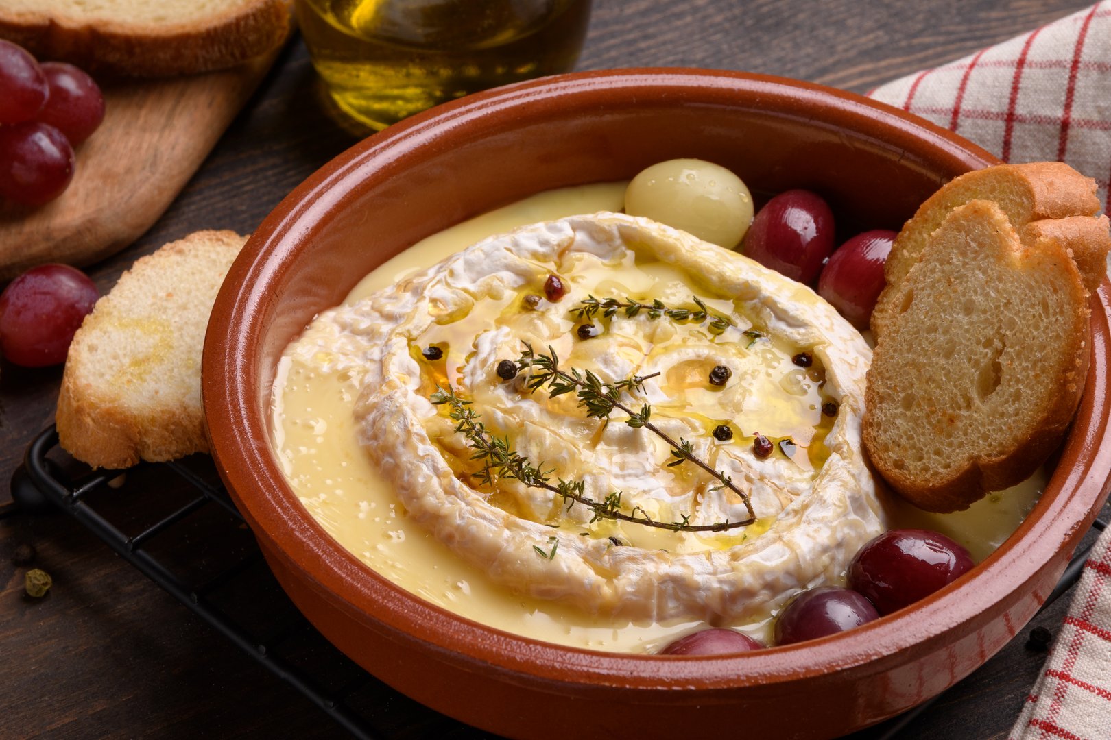 baked brie cheese with honey, grapes, aromatic herbs and crusty bread, baked camembert
