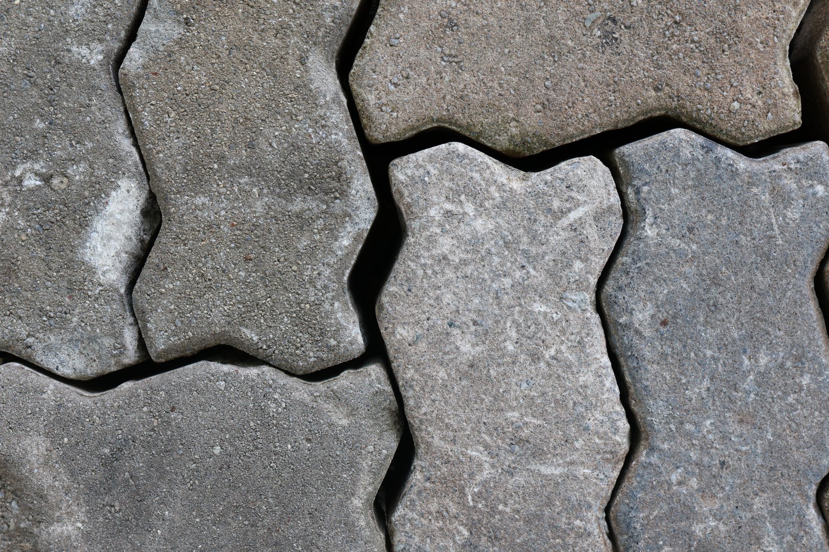 Close-up of gray interlocking paving stones with detailed texture. Ideal for backgrounds, design projects, or pattern references. Perfect for adding a natural, rugged look to your creative work.