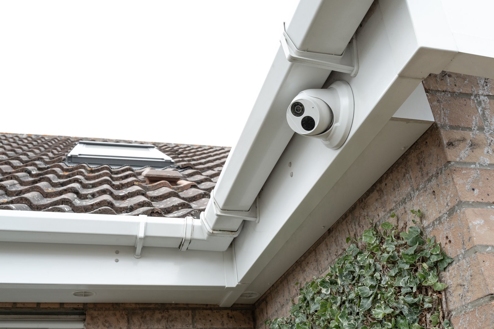 Newly installed dome CCTV night and day camera fitted to the eaves of a modern house, located on a housing estate in the UK.
