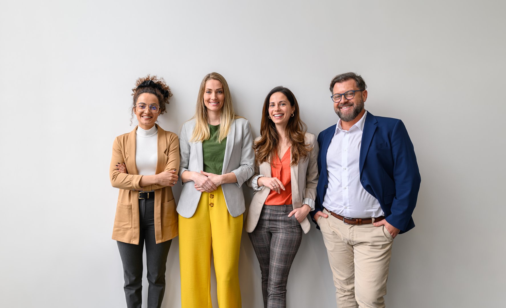 Portrait of confident businessman and female professionals standing together happily on white background