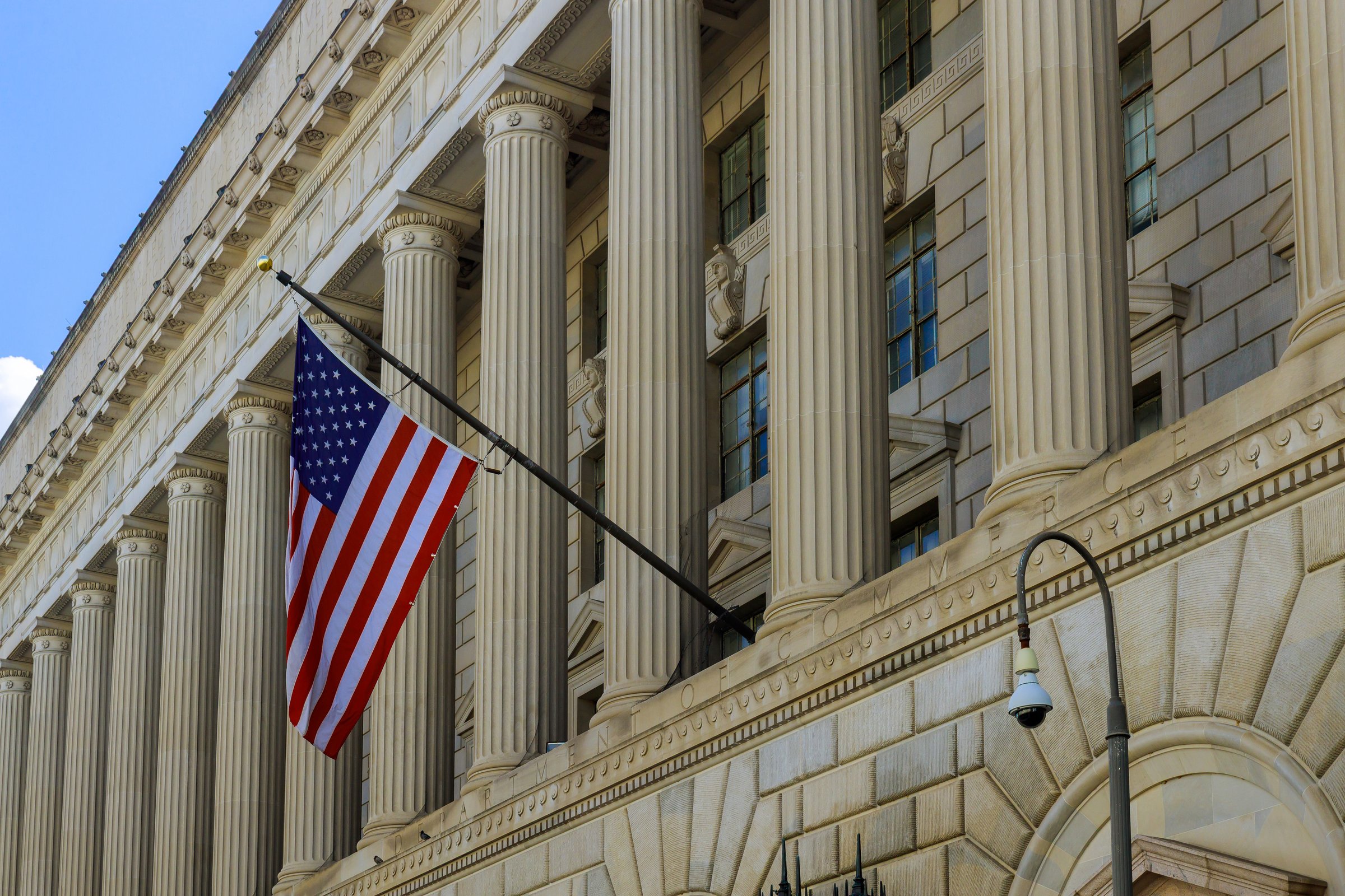 Flag waves proudly from architectural facade of historic government structure under Washington D.C