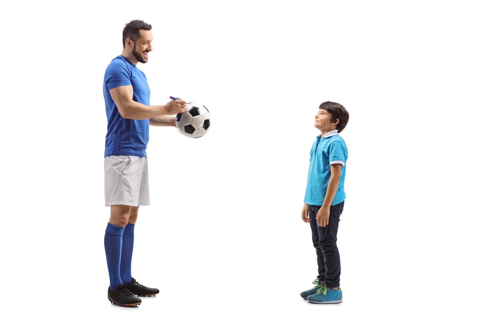 Full length profile shot of a footballer signing an autograph on a soccer ball for a boy fan isolated on white background