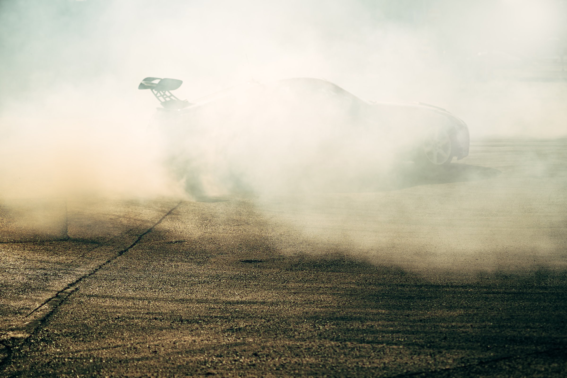 Car drifting on asphalt road, creating huge cloud of smoke during motorsport action