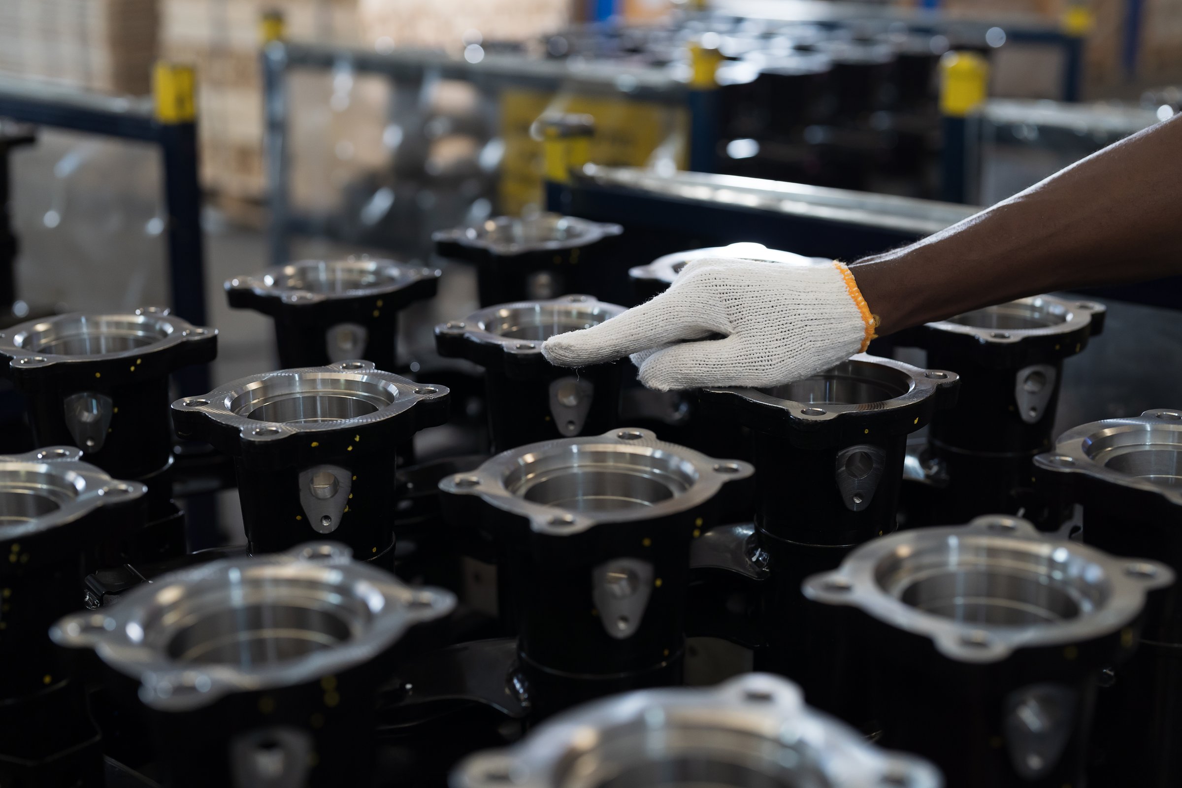 Hand of male warehouse worker wear safety uniform, helmet and inspecting quality of products in storage warehouse