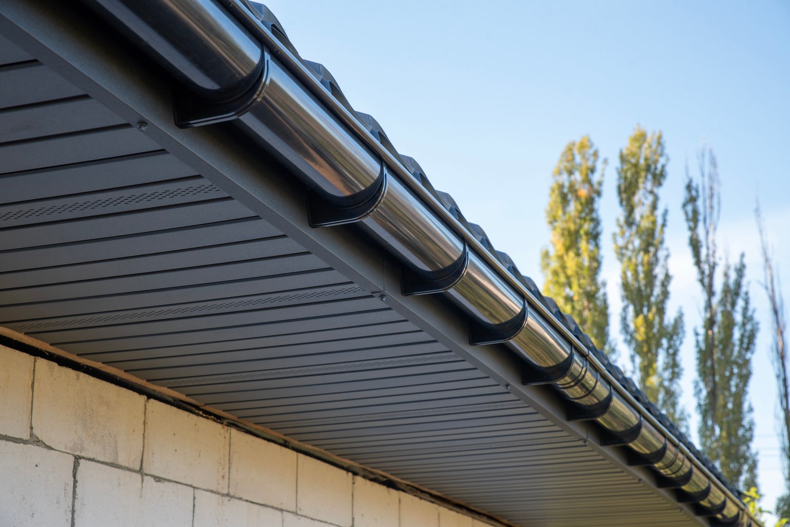 Gray plastic gutter system on roof overhang close up