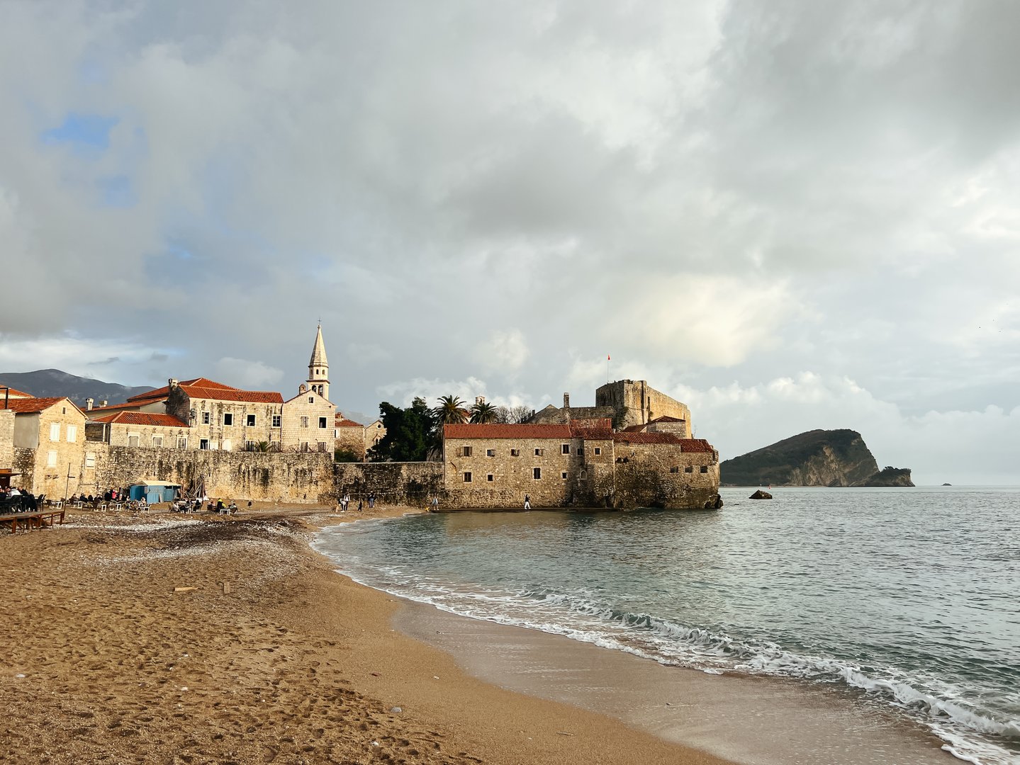 Sandy beach near the stone fortress wall of the old town of Budva. Montenegro. High quality photo
