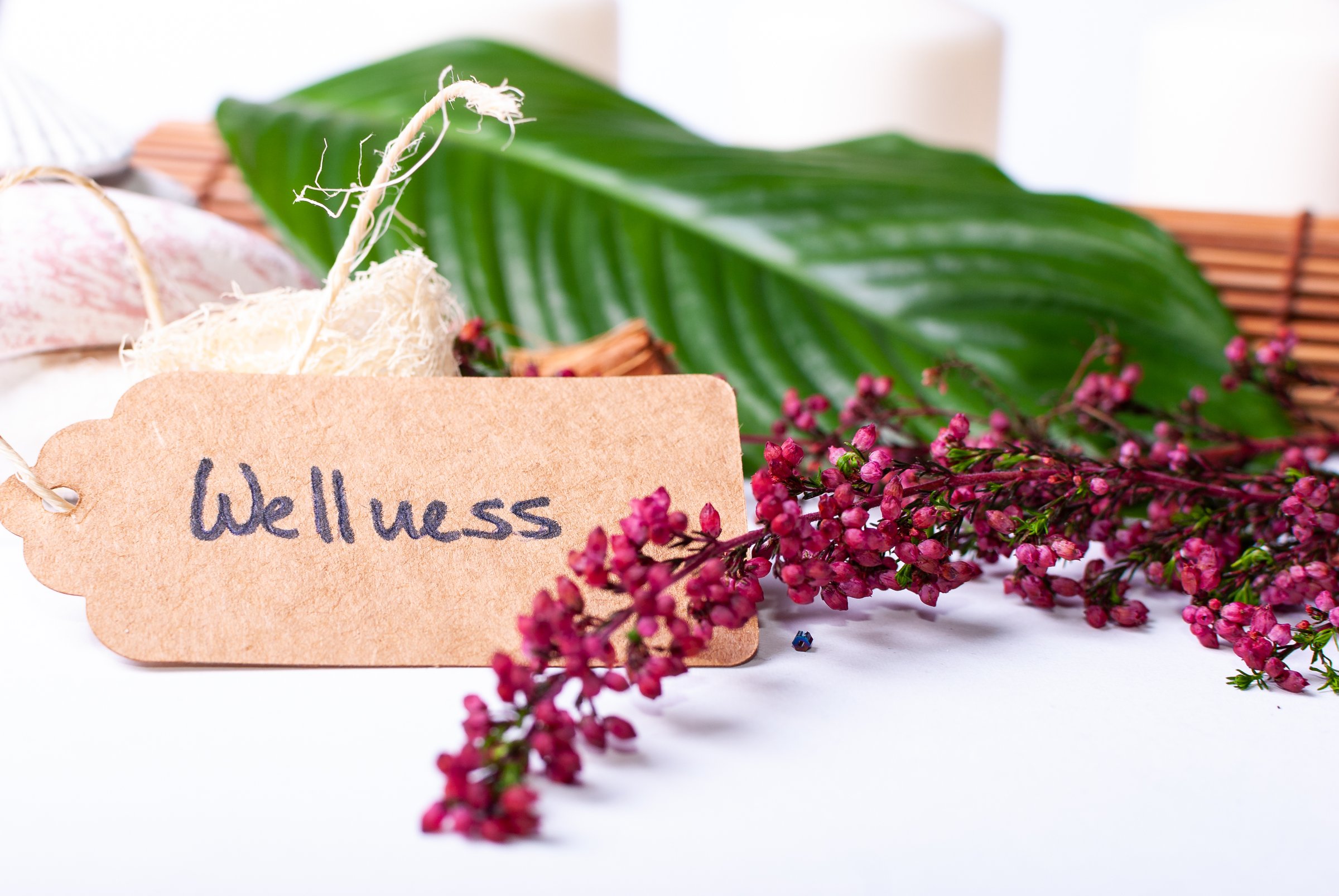 Close up of a set up of wellness items with copy space, a bamboo mat, candles, stones, a branch, a leaf