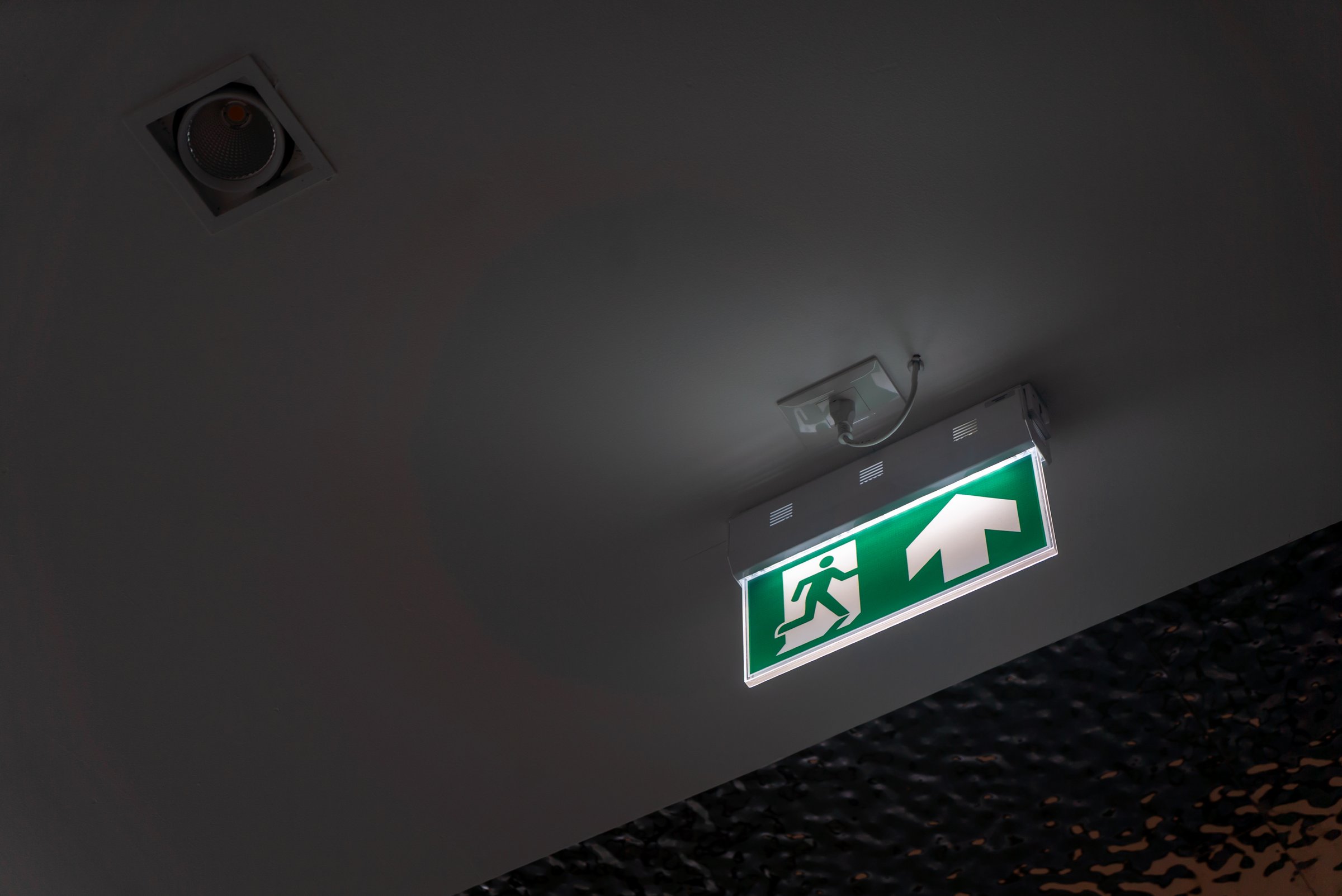 A vibrant exit sign mounted on the ceiling, providing clear instructions for safety and guidance in an emergency situation indoors. Ideal for design and safety concepts.