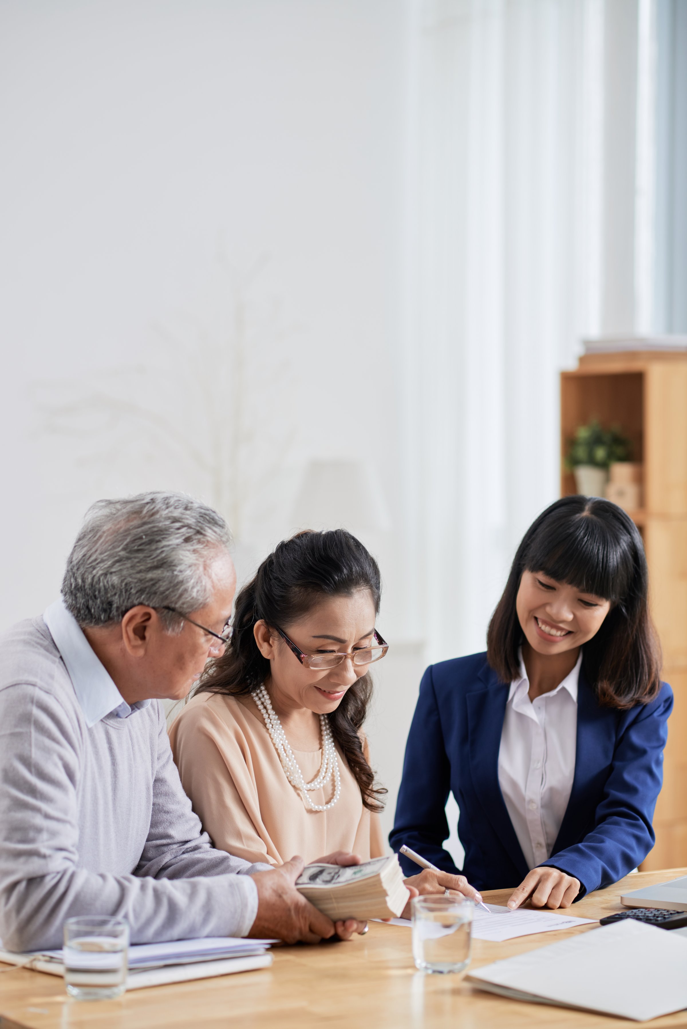Smiling real estate agent asking senior couple to sign document after they pay deposit for house