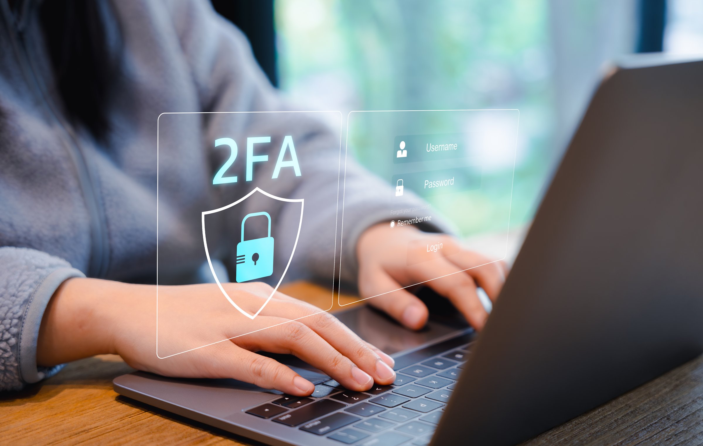 Two-Factor Authentication for Cyber Security. Person using a laptop with a digital screen displaying a shield icon and 2FA representing two-factor authentication and enhanced cyber security measures