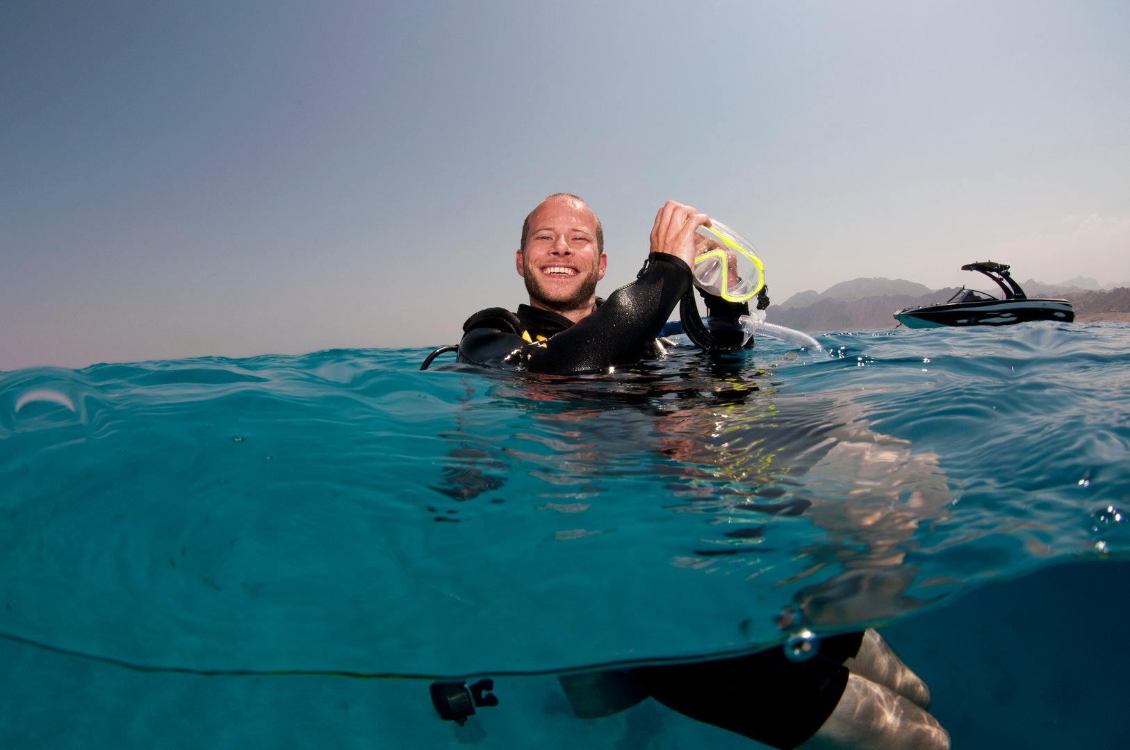 male scuba diver cleans his mask on the surface before a scuba dive