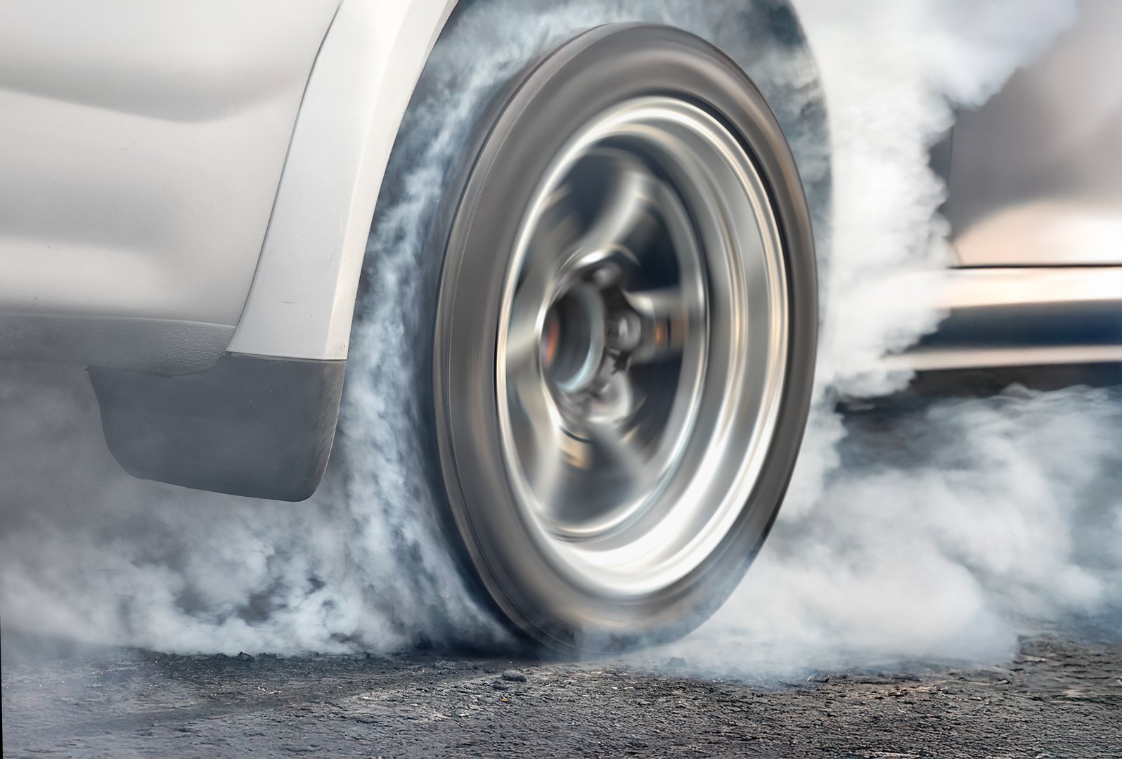 Drag racing car is burning tires at start line.