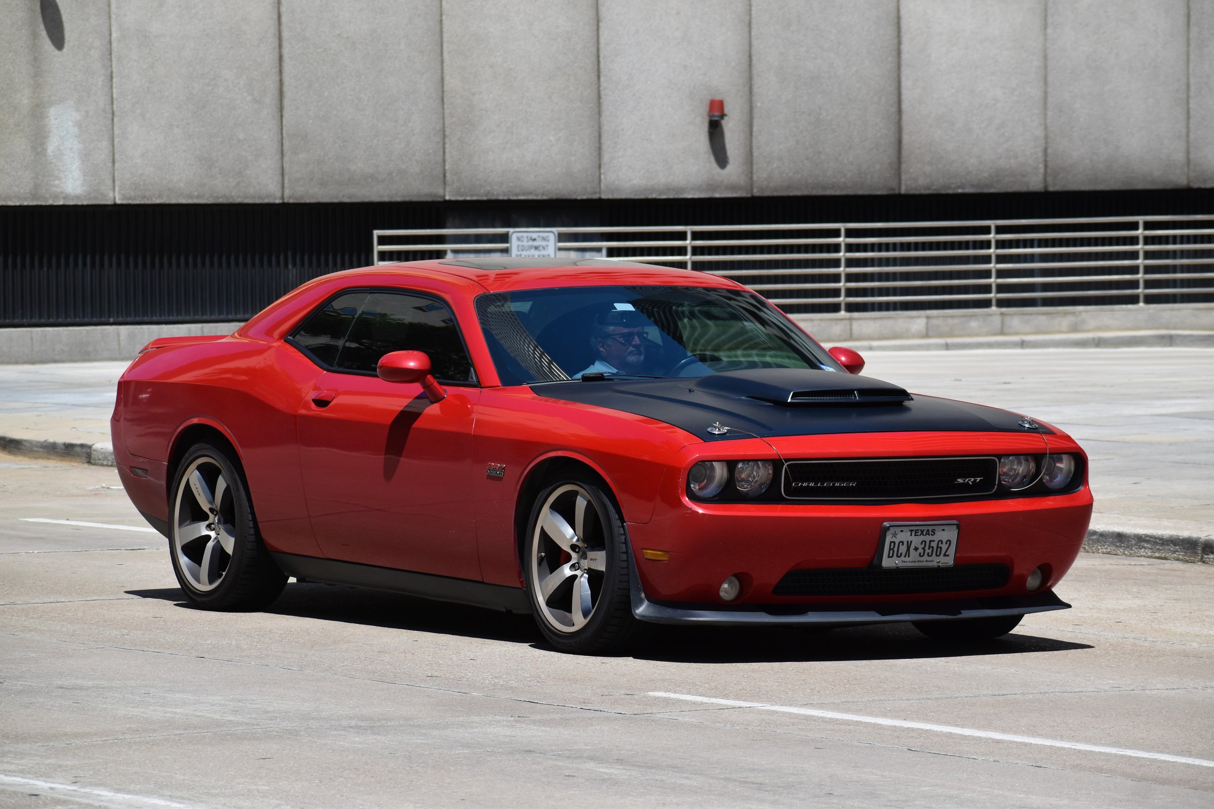 Houston, TX USA - 5/11/2024 - A portrait of a red and black Dodge Challenger sports car traveling in a downtown district