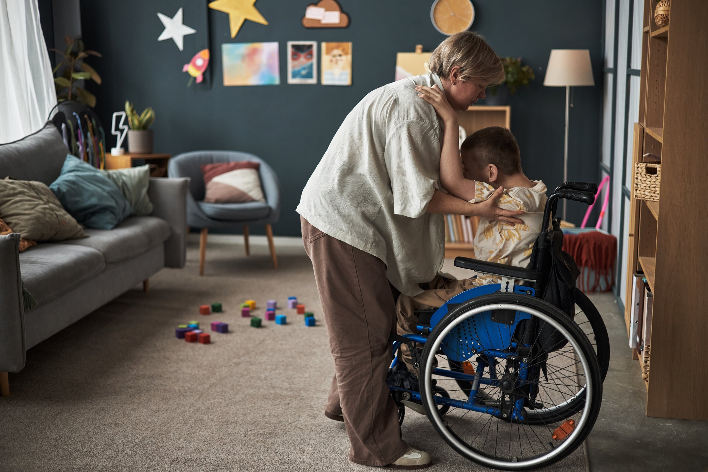 Adult assisting child with family in family-friendly living room decorated with artwork and toys, creating supportive environment