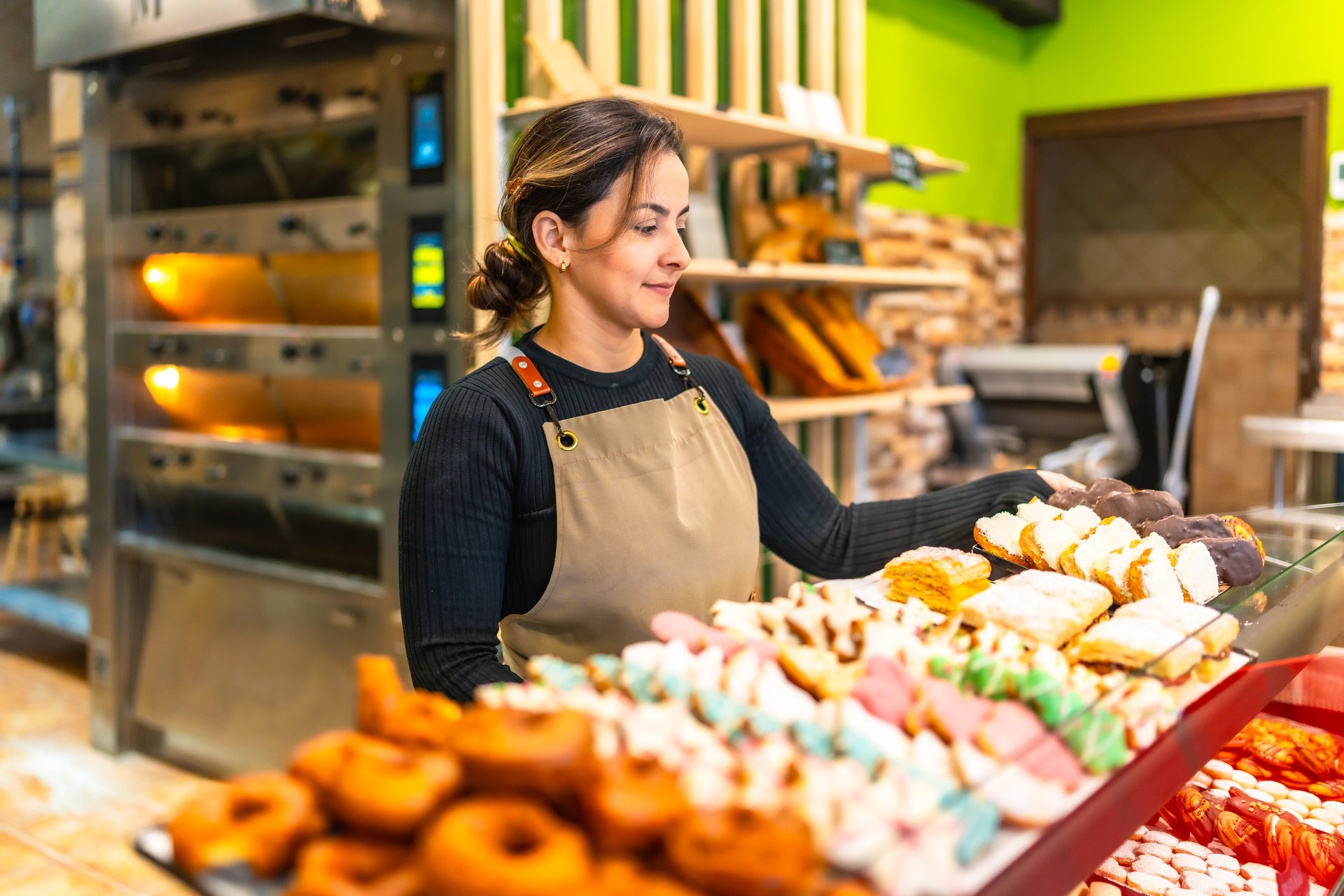 Side view photo with copy space of a latin young friendly woman selling bread and pastries in an artisan bakery