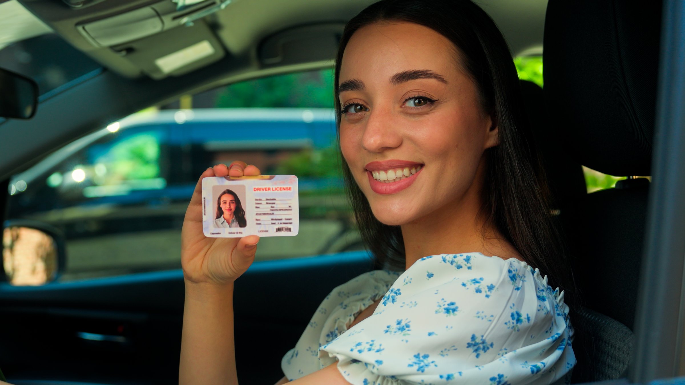 Happy smiling Caucasian joyful girl woman female driver sitting inside new car showing driving license at camera successfully passed test exam drive courses. Transportation test drive automobile rent. High quality 4k footage