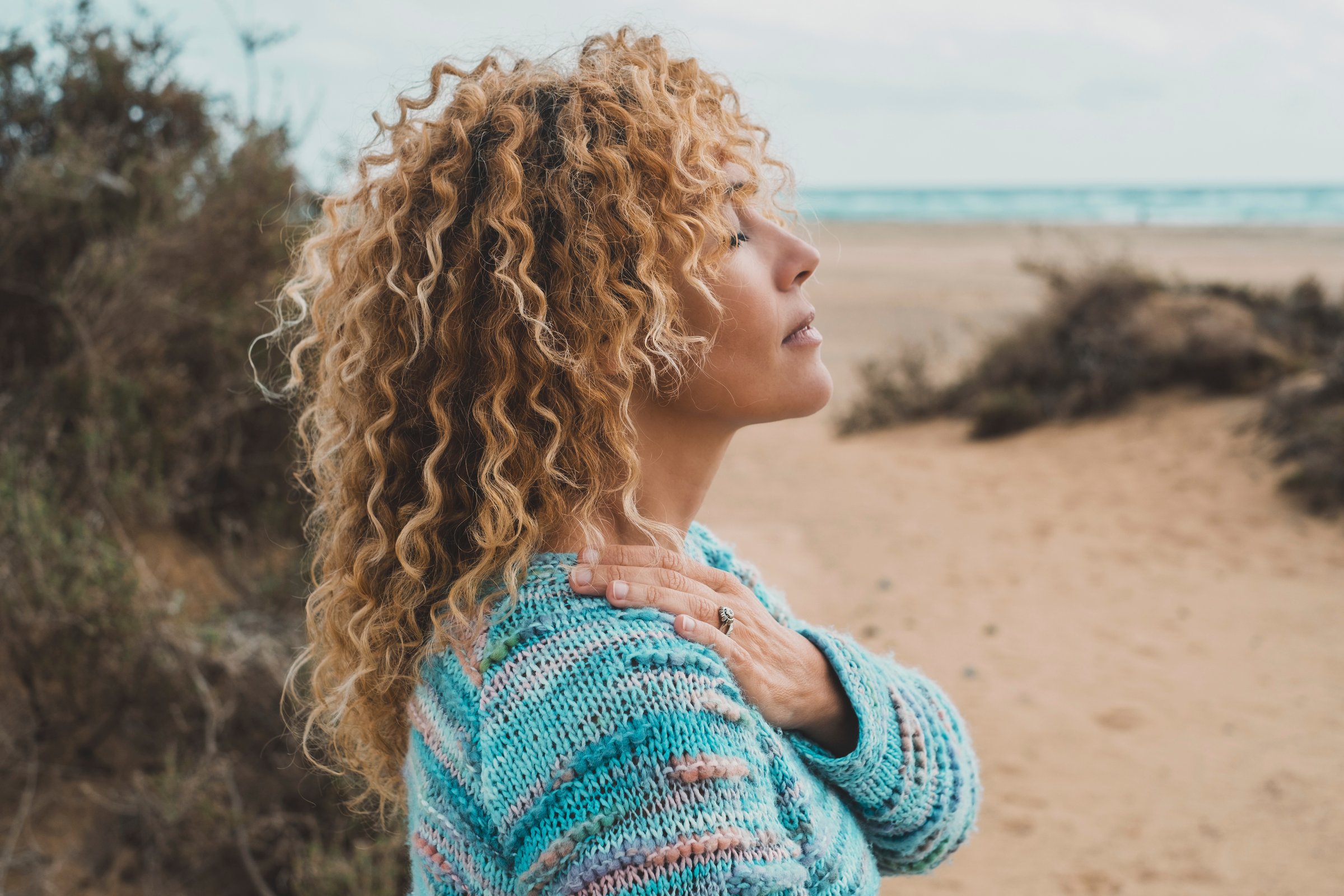 One woman enjoy inner balance and meditation leisure outdoor activity alone feeling nature hugging herself at the beach. Side portrait of zen lifestyle and happiness female people. Closed eyes love