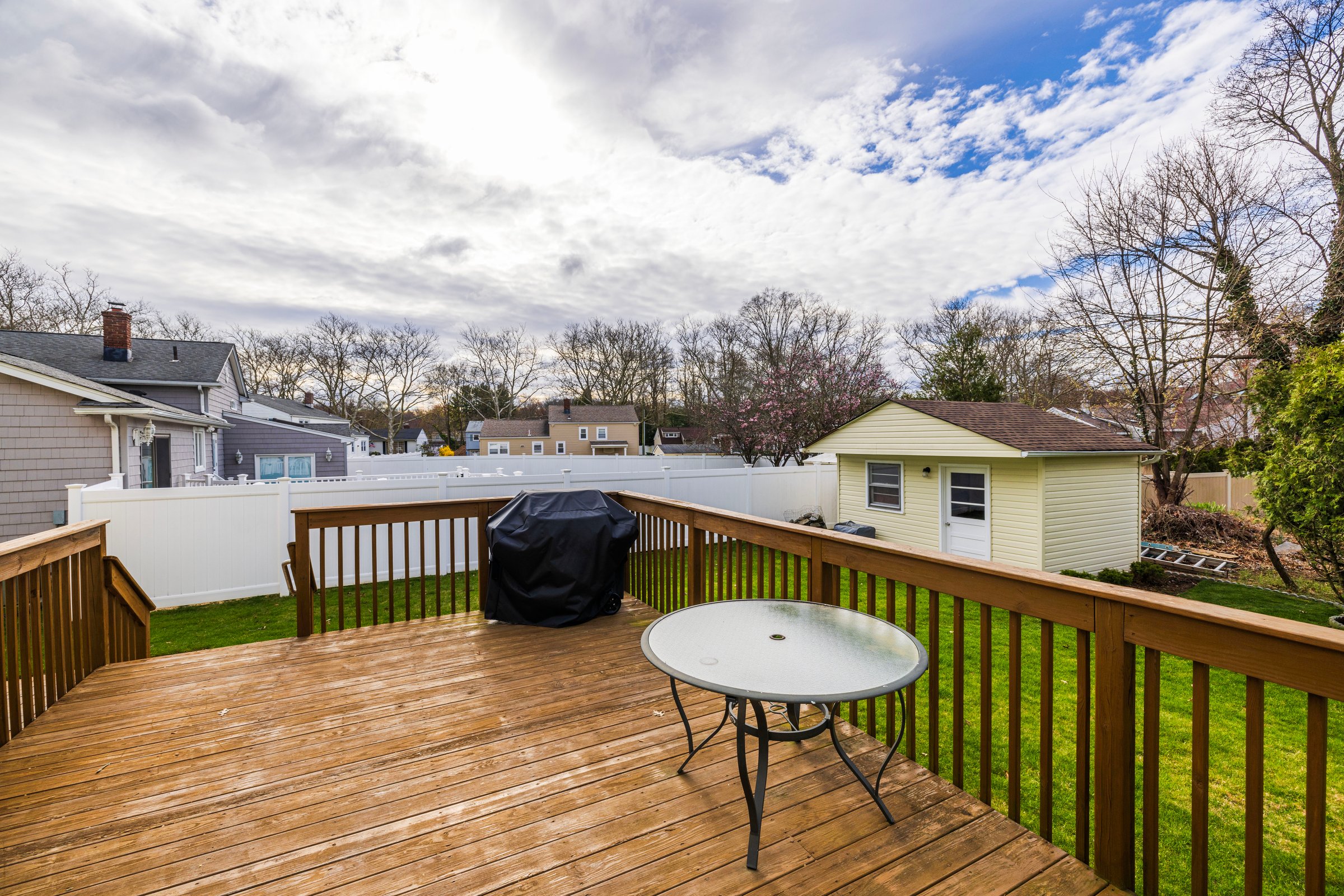 Beautiful spring view of backyard villa with patio, green lawn, garden shed, and outdoor furniture with barbecue