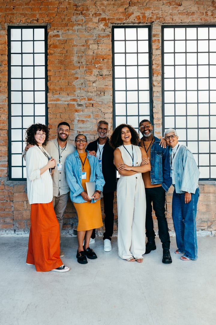 Diverse group of business managers standing together, showcasing team diversity and positive workplace environment in a modern office setting.