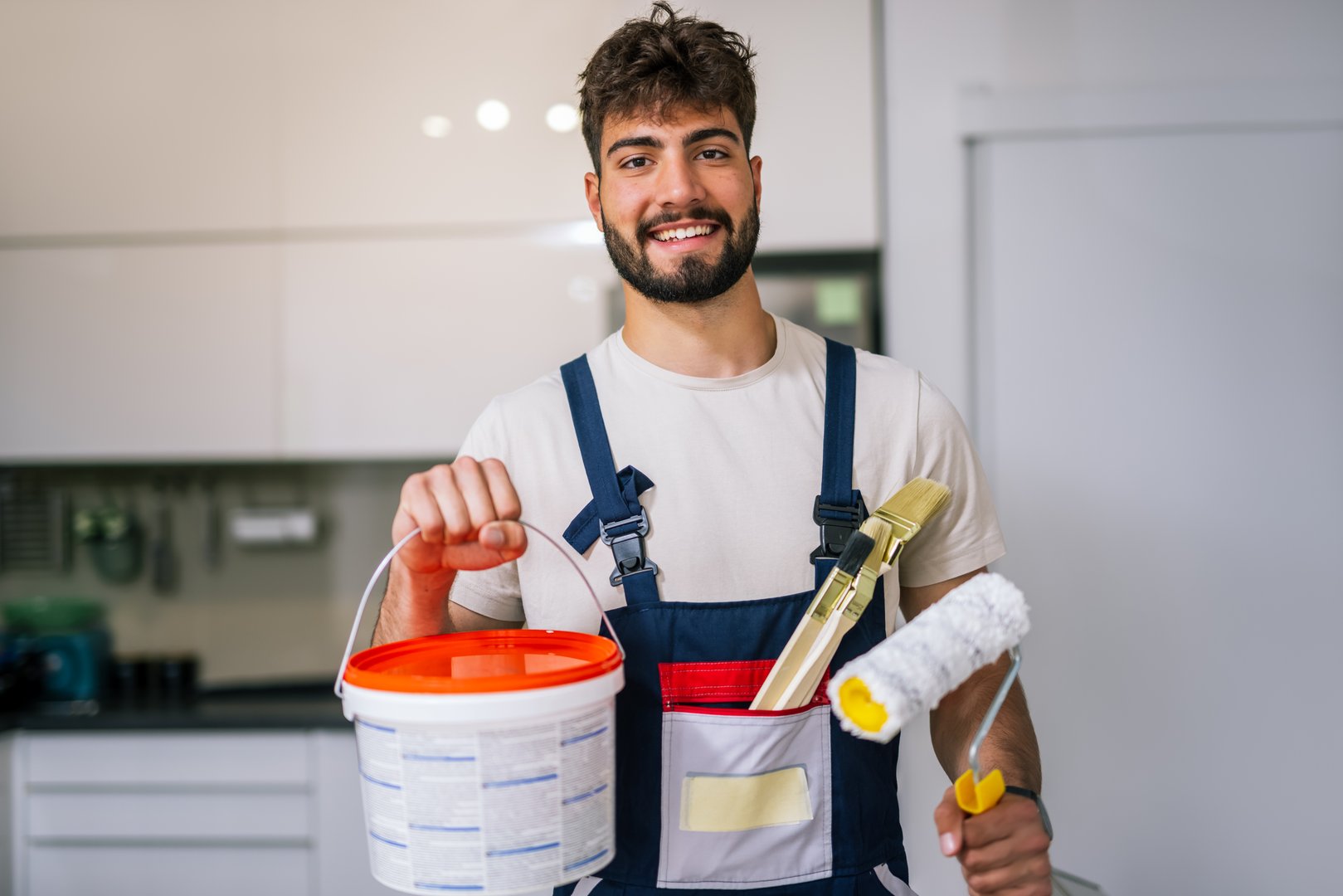 Painter in an apartment prepares to paint walls, holding lime and brushes, ready to start a fresh and precise renovation.