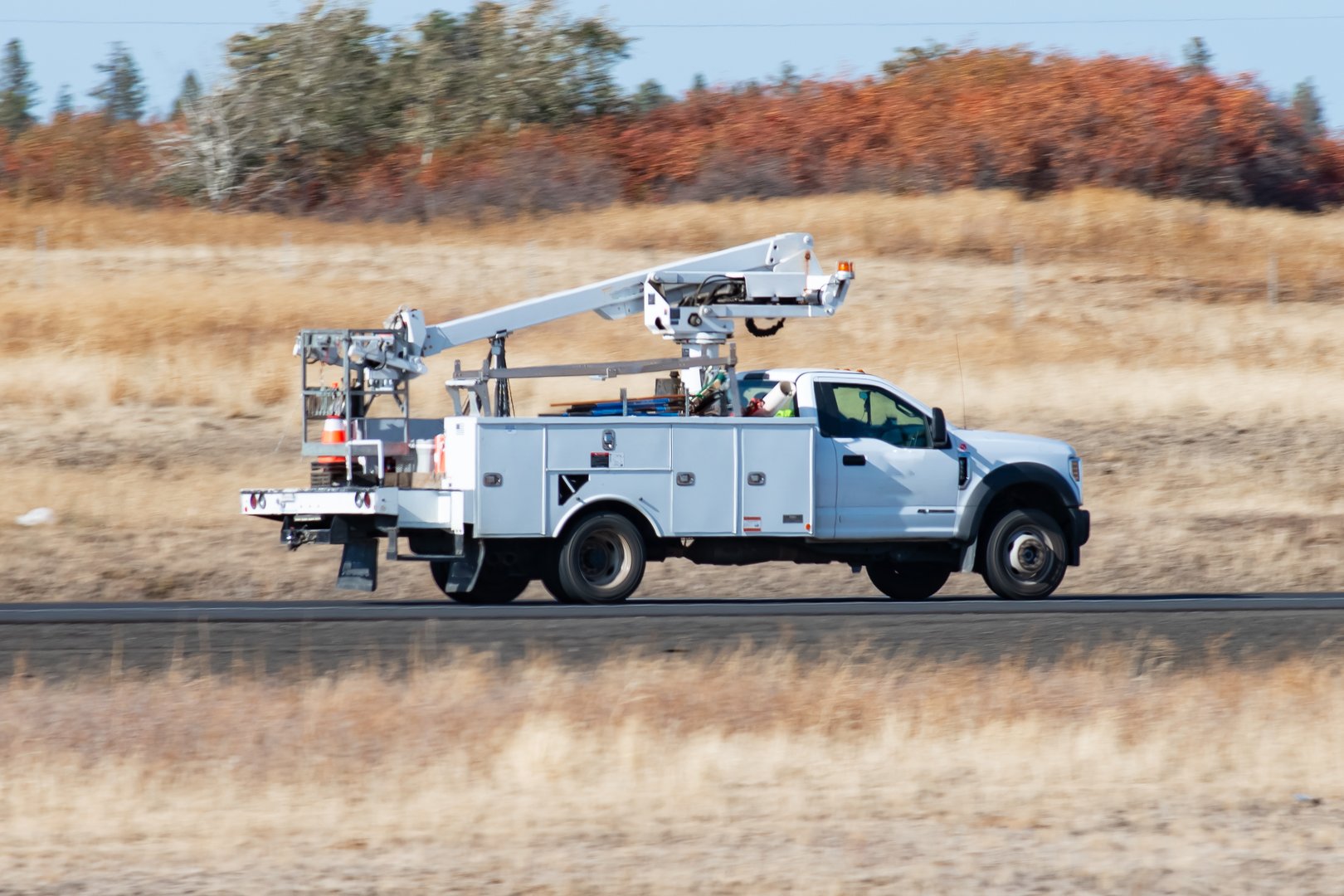 October 11, 2024
Tyler, Washington USA
A Utility company's cherry picker bucket truck driving along a rural section of interstate freeway.
