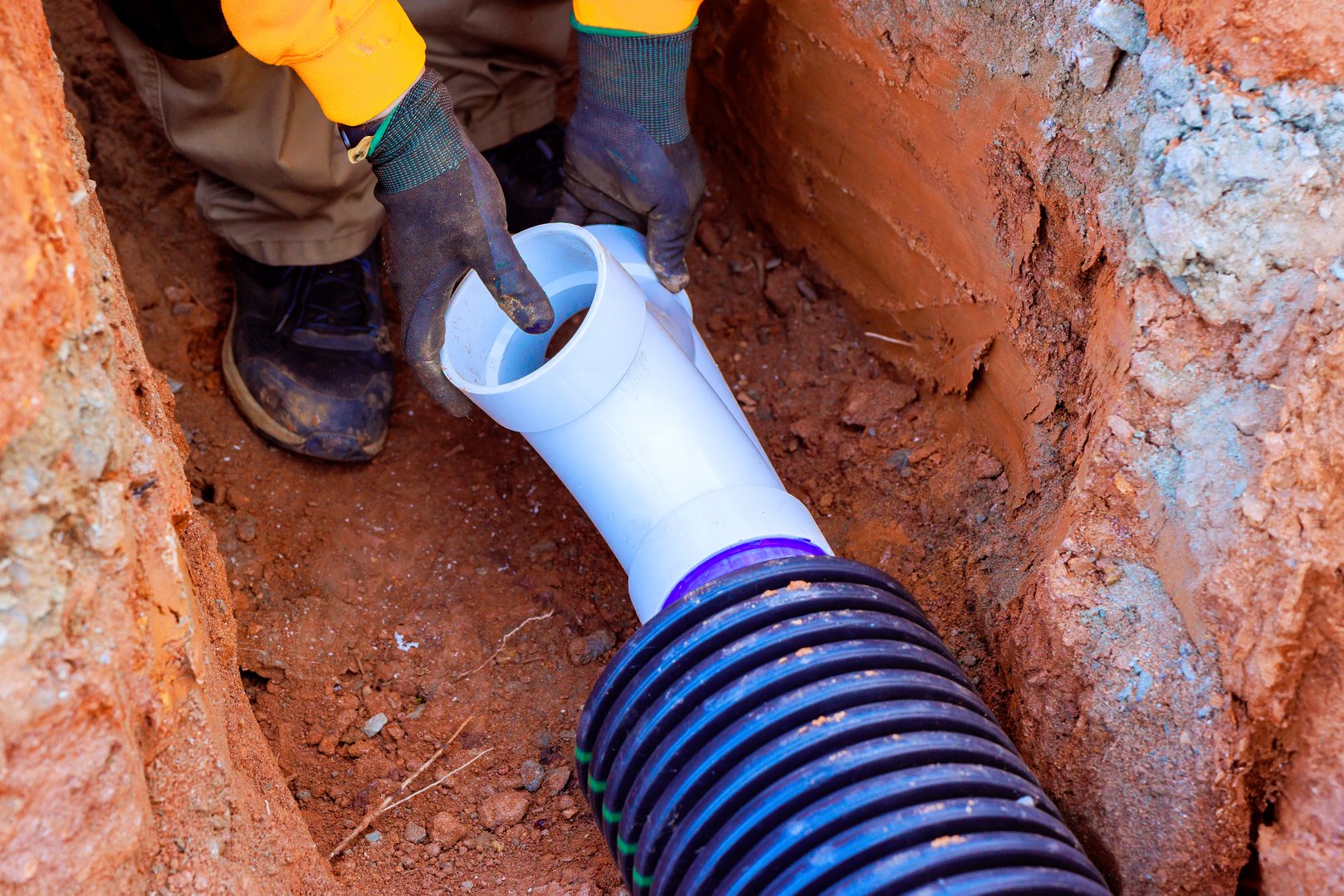 Construction worker connect drainage pipes in trench to ensure drainage water flow at construction site
