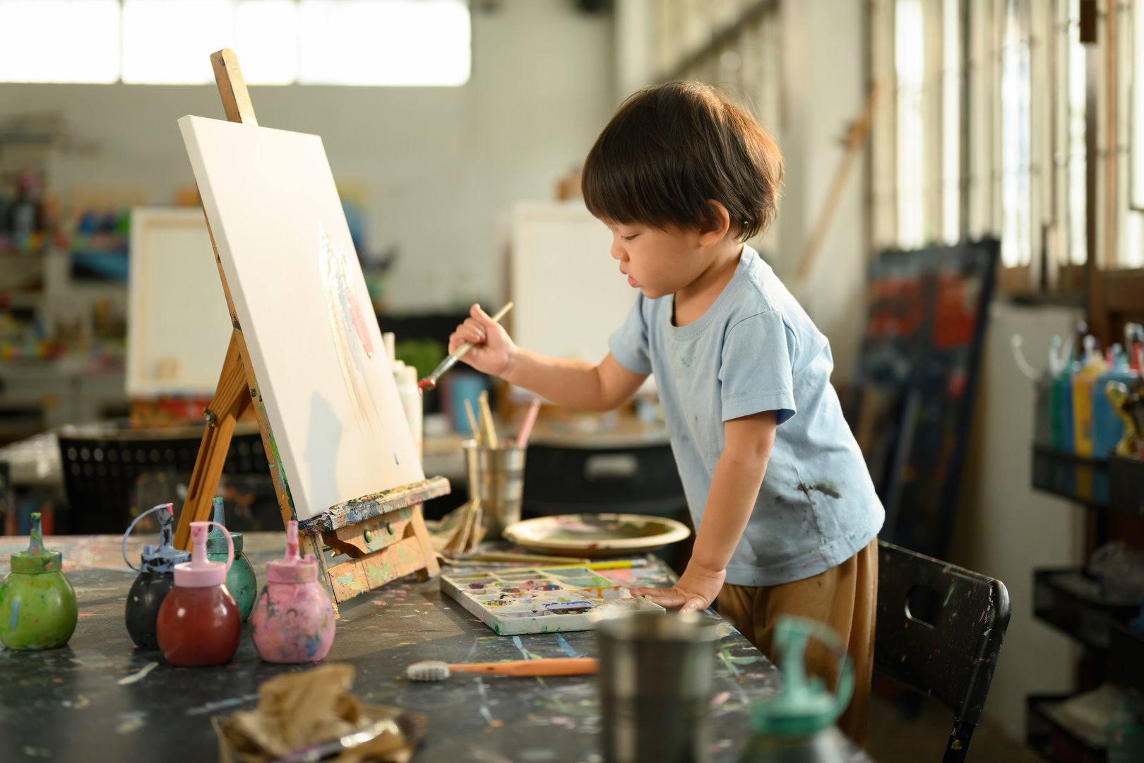Young child enjoying creative expression through painting in a preschool art environment.