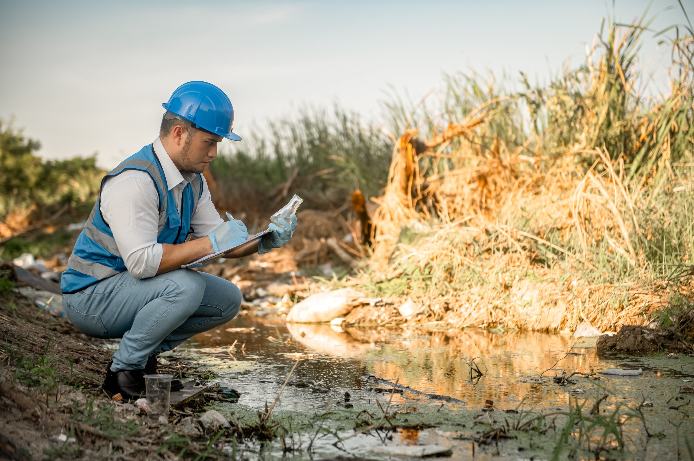 Water resources engineers inspect the quality of a canal in a community filled with garbage.