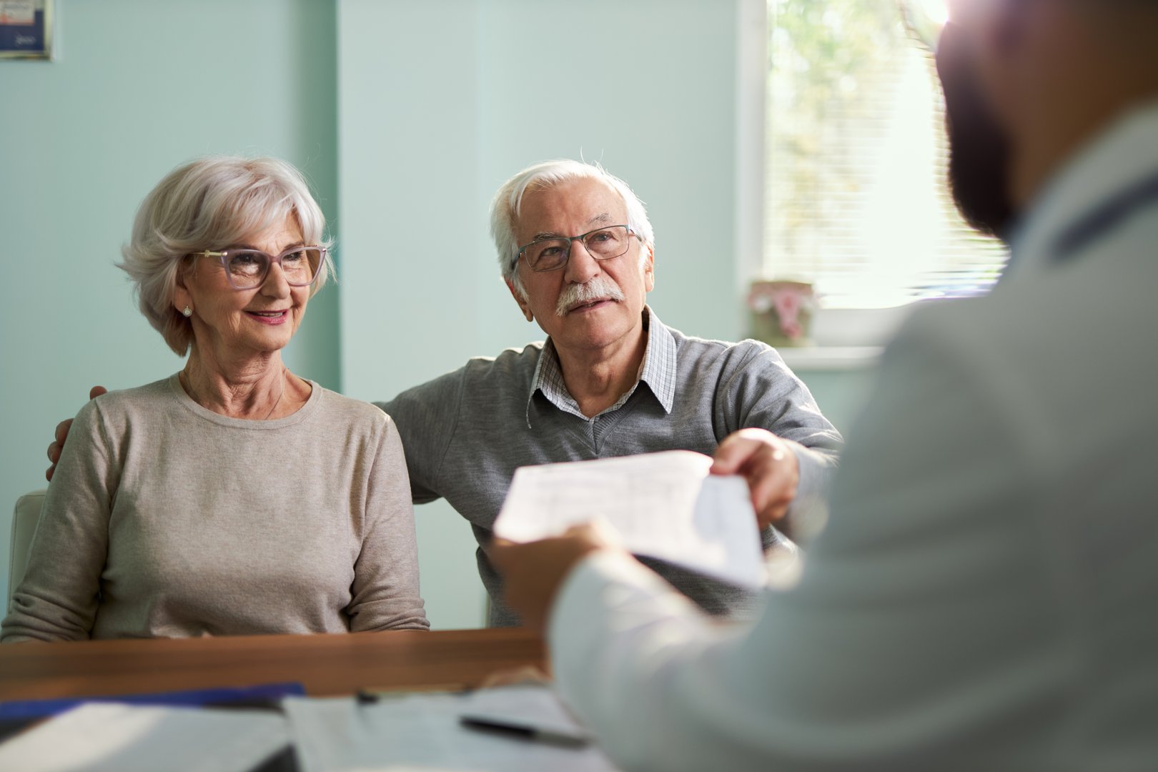 Doctor giving paperwork to his patients during an appointment in the office.